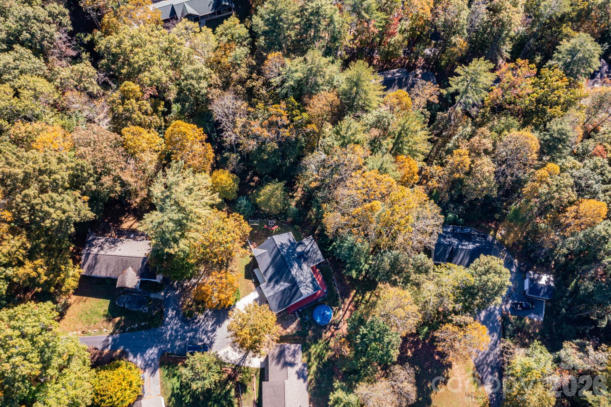 Overhead aerial highlighting the home’s placement among mature trees and its relationship to neighboring properties. - 139 Lone Eagle Lane, Hendersonville
