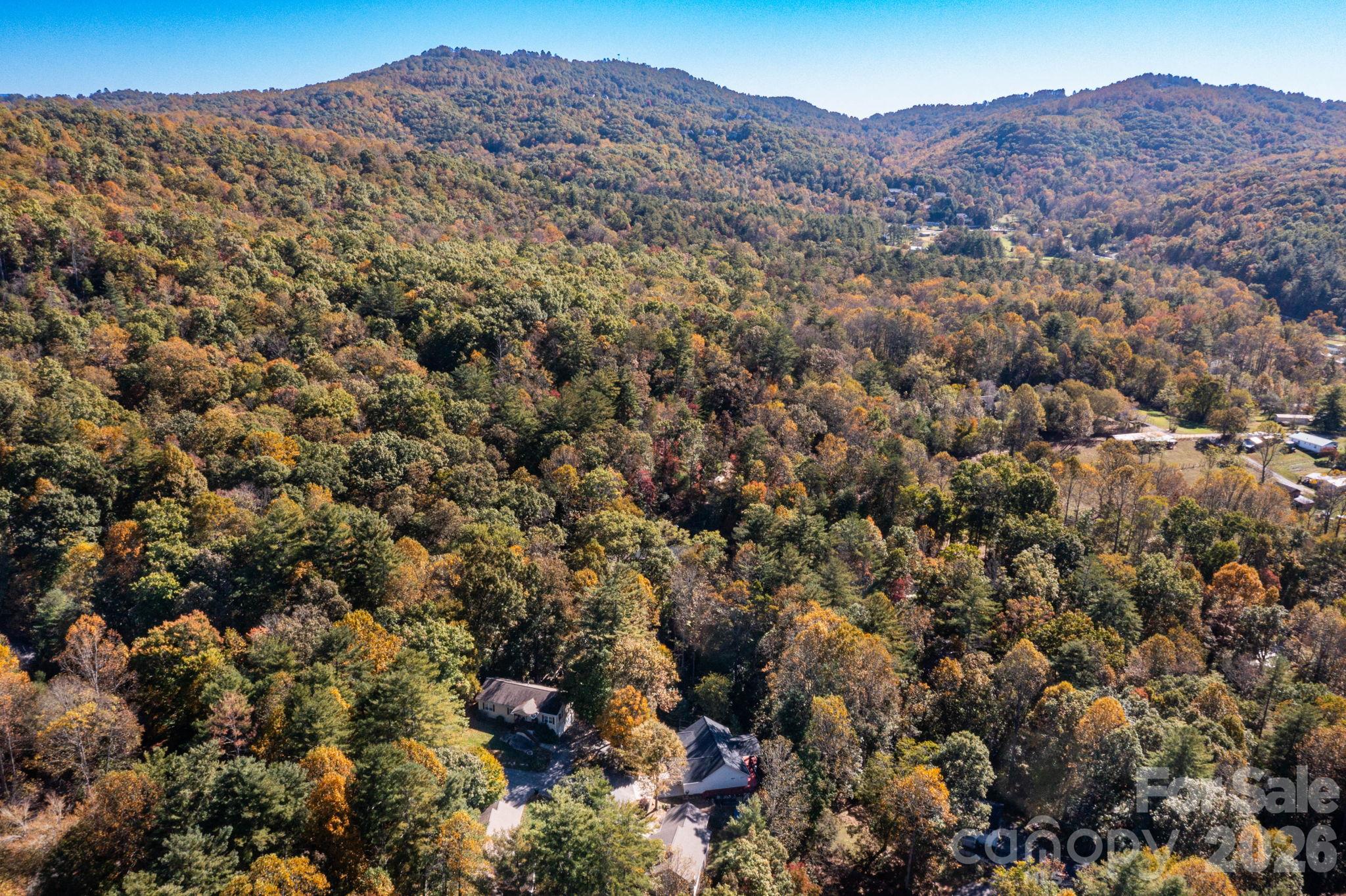 Aerial perspective showcasing the surrounding wooded hills, nearby homes, and autumn mountain scenery. - 139 Lone Eagle Lane, Hendersonville