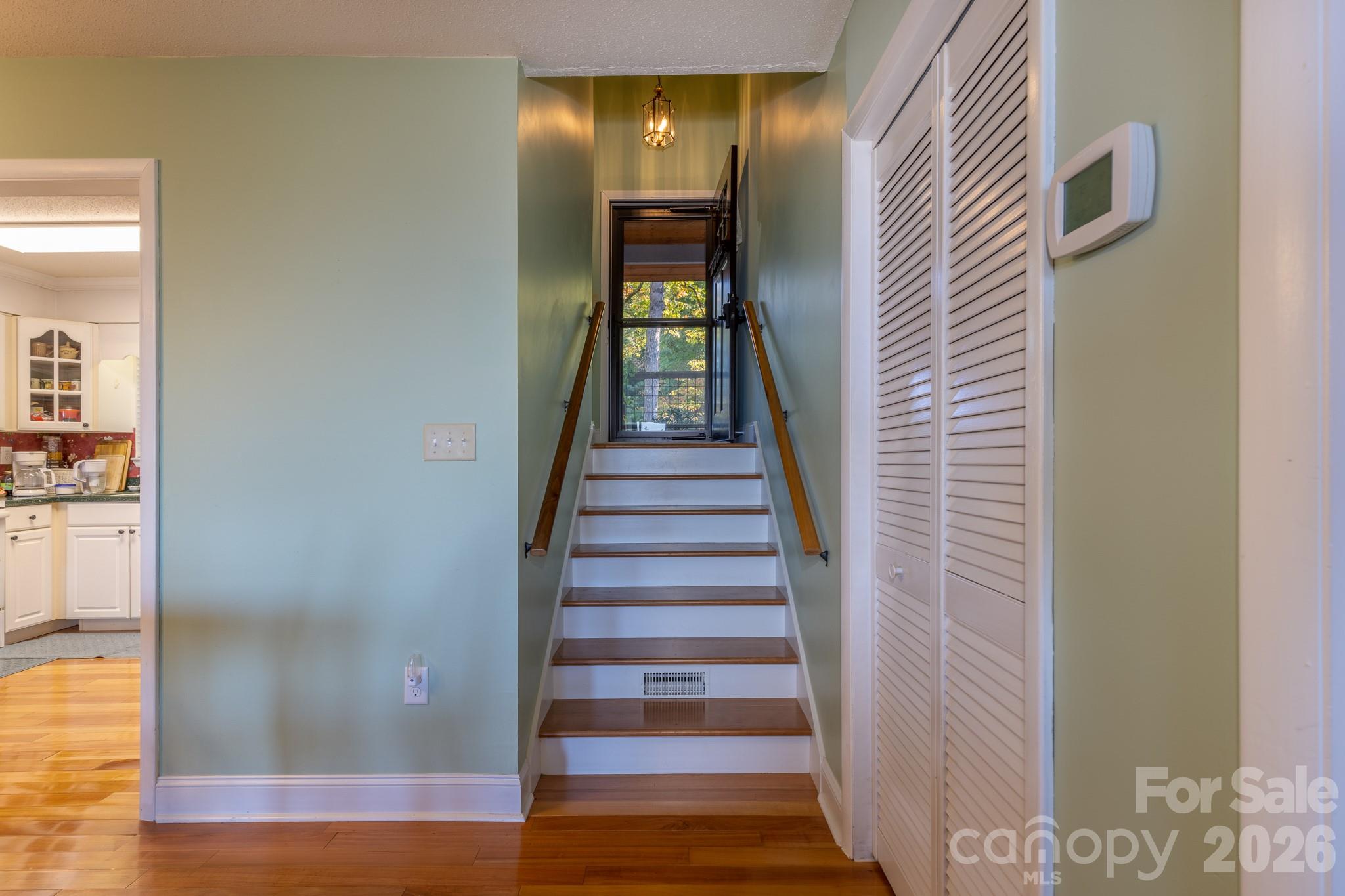 Interior stairway featuring hardwood treads, dual handrails, and convenient access to the upper level. - 524 Three Mile Knob Road, Pisgah Forest