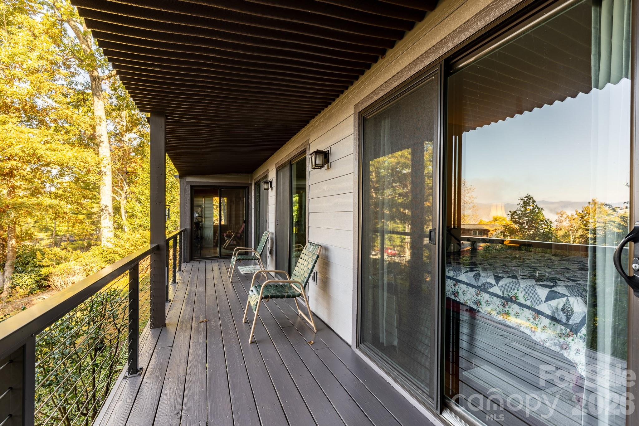 Expansive covered deck with durable decking, cable railing, and peaceful wooded surroundings. A wonderful place to relax and enjoy mountain living. - 524 Three Mile Knob Road, Pisgah Forest