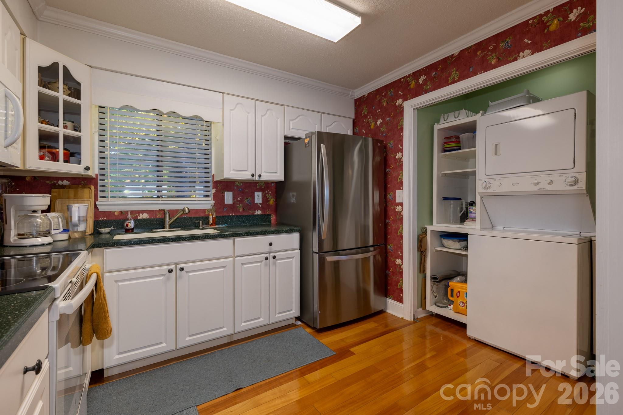 Additional kitchen view showing convenient access to the laundry area, ample cabinetry, and attractive hardwood flooring. - 524 Three Mile Knob Road, Pisgah Forest