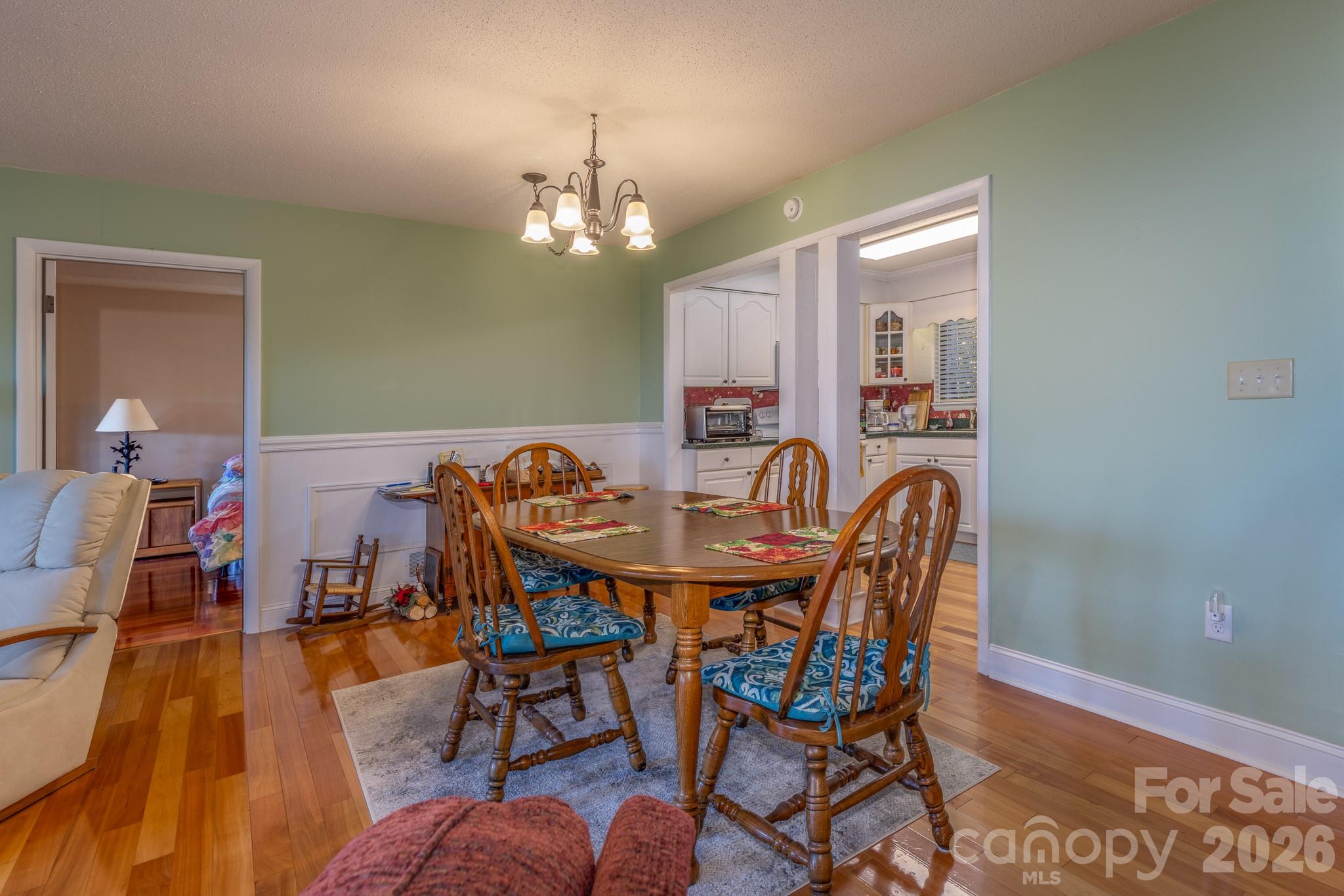 Spacious dining room with attractive hardwood flooring, decorative chair rail, and easy access to the kitchen and adjoining living areas - 524 Three Mile Knob Road, Pisgah Forest