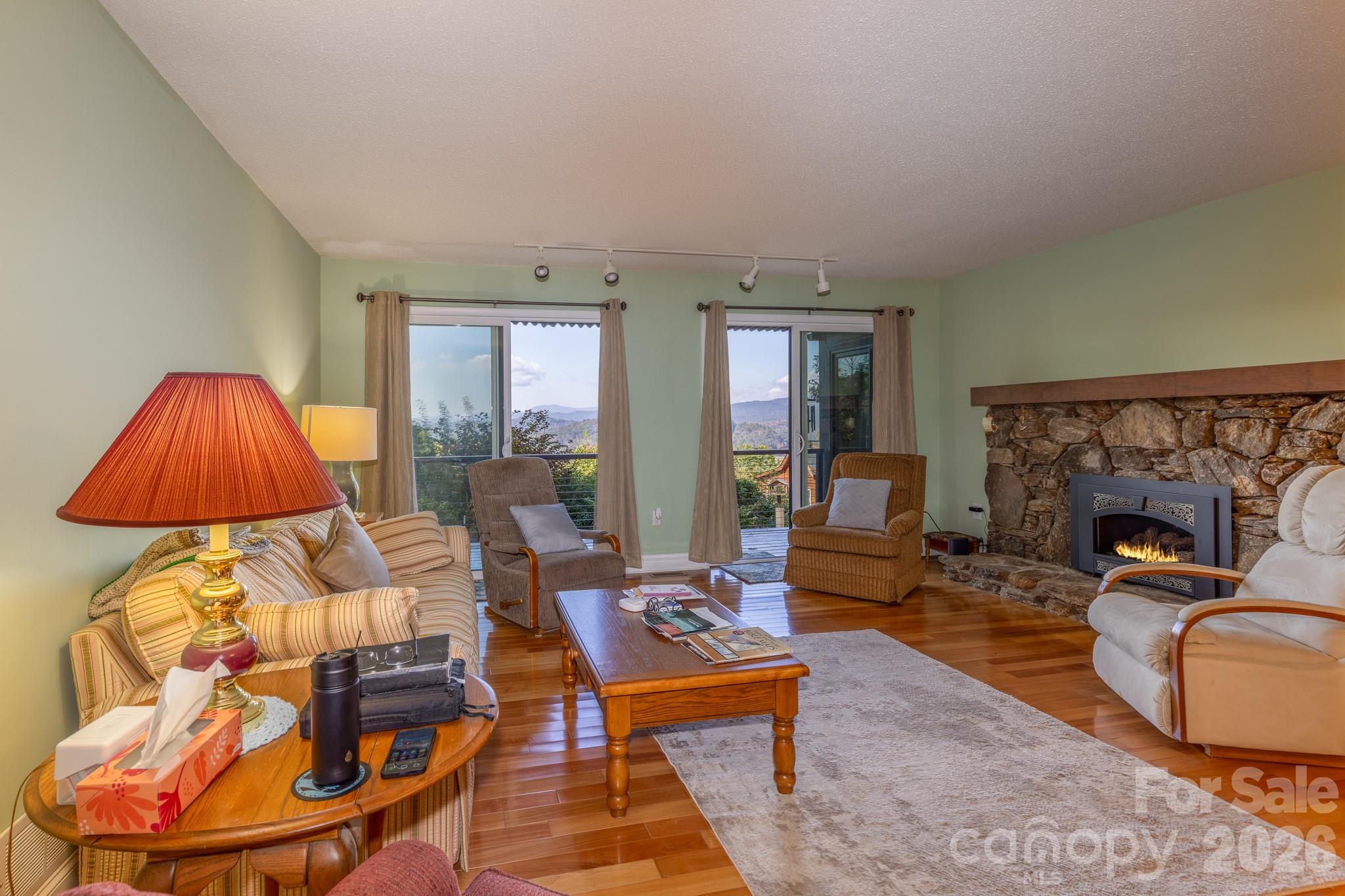 Impressive native stone fireplace with handsome solid wood mantel, gas fireplace insert, and raised stone hearth. A beautiful focal point that adds warmth and mountain character to the living room. - 524 Three Mile Knob Road, Pisgah Forest