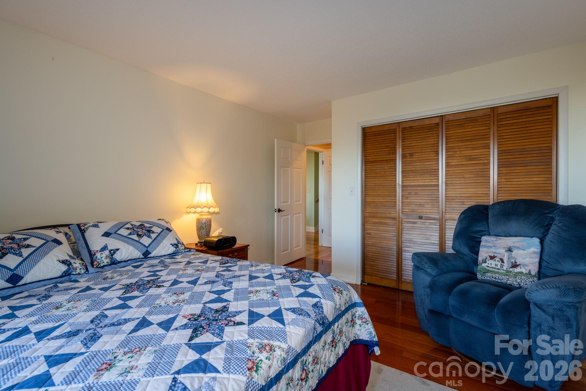 Comfortable bedroom featuring hardwood flooring, generous closet space, and room for additional seating - 524 Three Mile Knob Road, Pisgah Forest