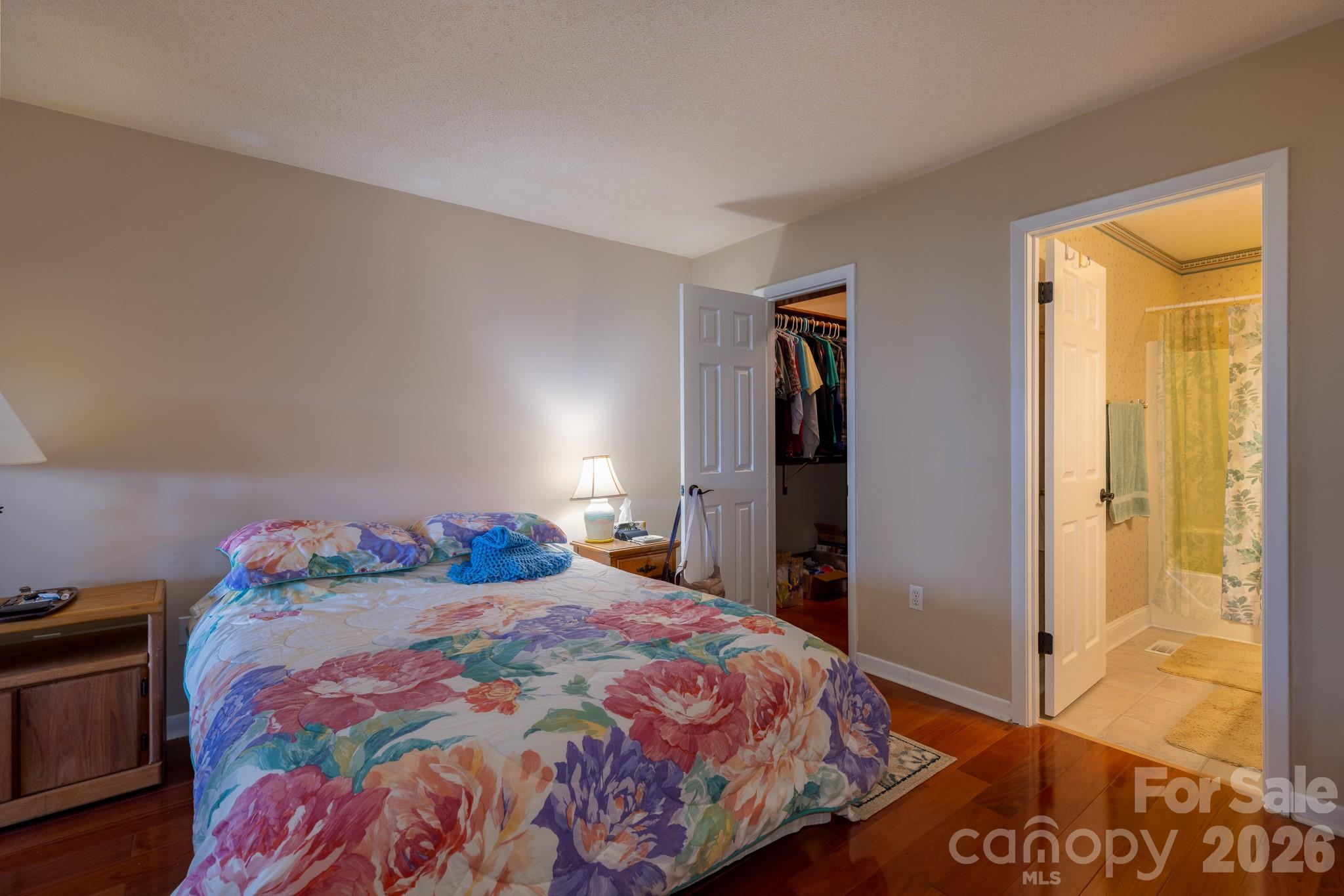 Spacious bedroom with hardwood flooring, closet access, and convenient entry to an adjoining full bathroom featuring a tub/shower combination. - 524 Three Mile Knob Road, Pisgah Forest