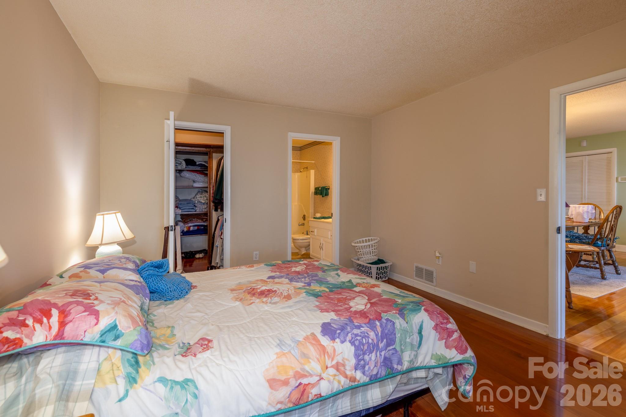 Comfortable primary bedroom featuring hardwood flooring, a spacious walk-in closet, and convenient access to the full bathroom - 524 Three Mile Knob Road, Pisgah Forest