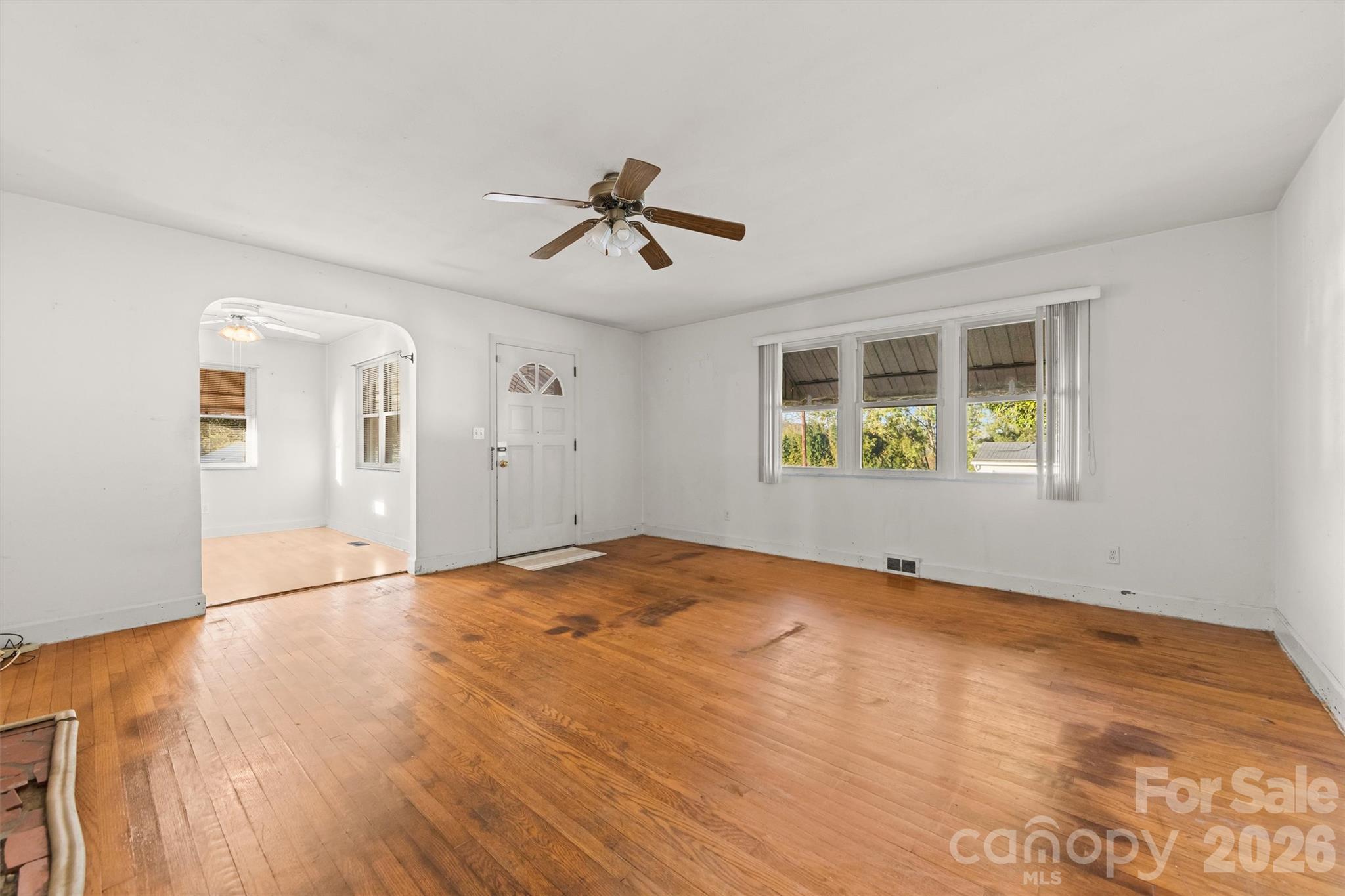 Front windows in the living room with original wood floors and brick fireplace - 108 Morgan Street, Canton