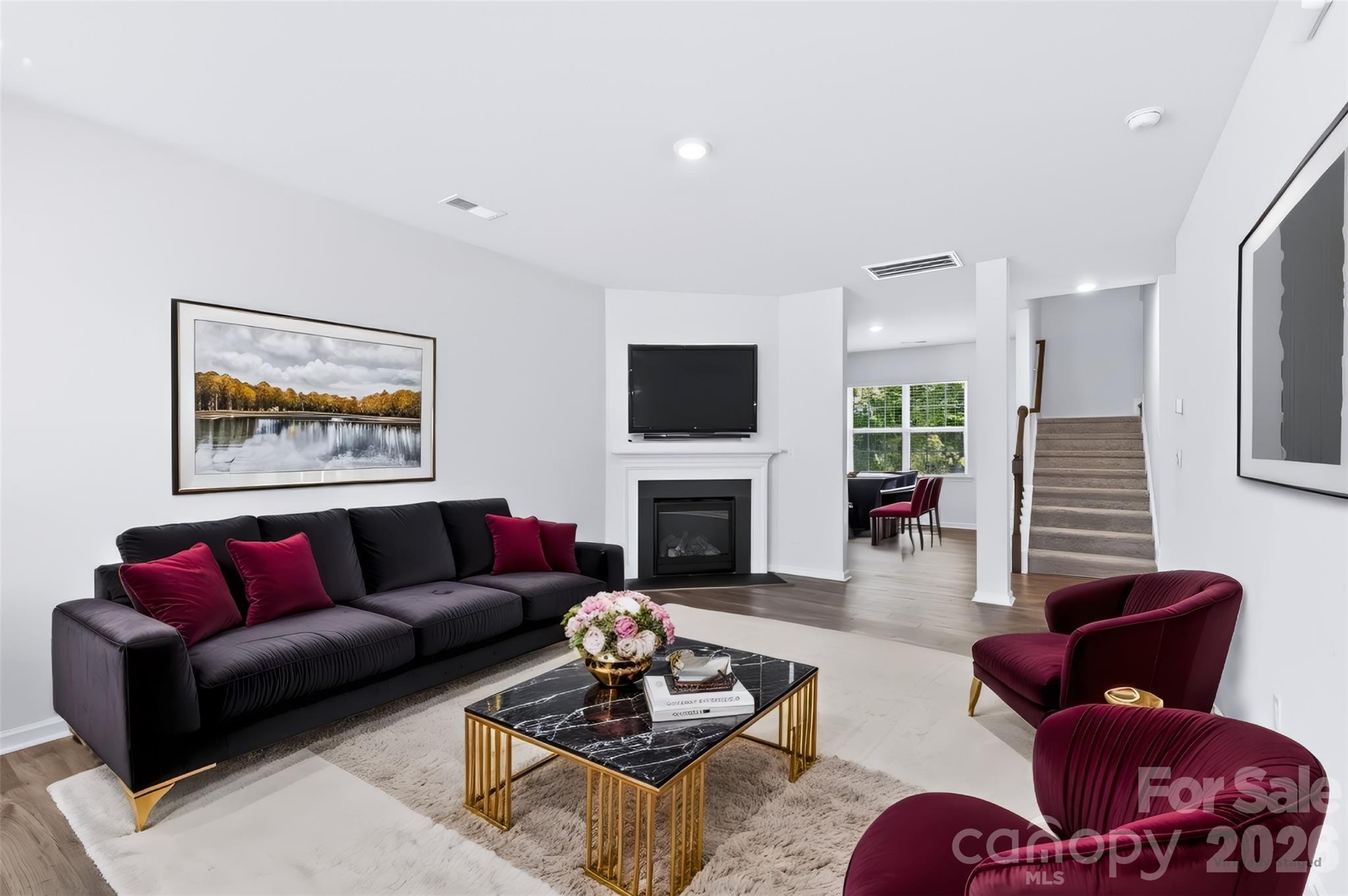 Unwind in the cozy living room, featuring low-maintenance LVP flooring and a warm gas-log fireplace with a classic slate surround and mantel. - 3741 Stanley Creek Drive, Mount Holly