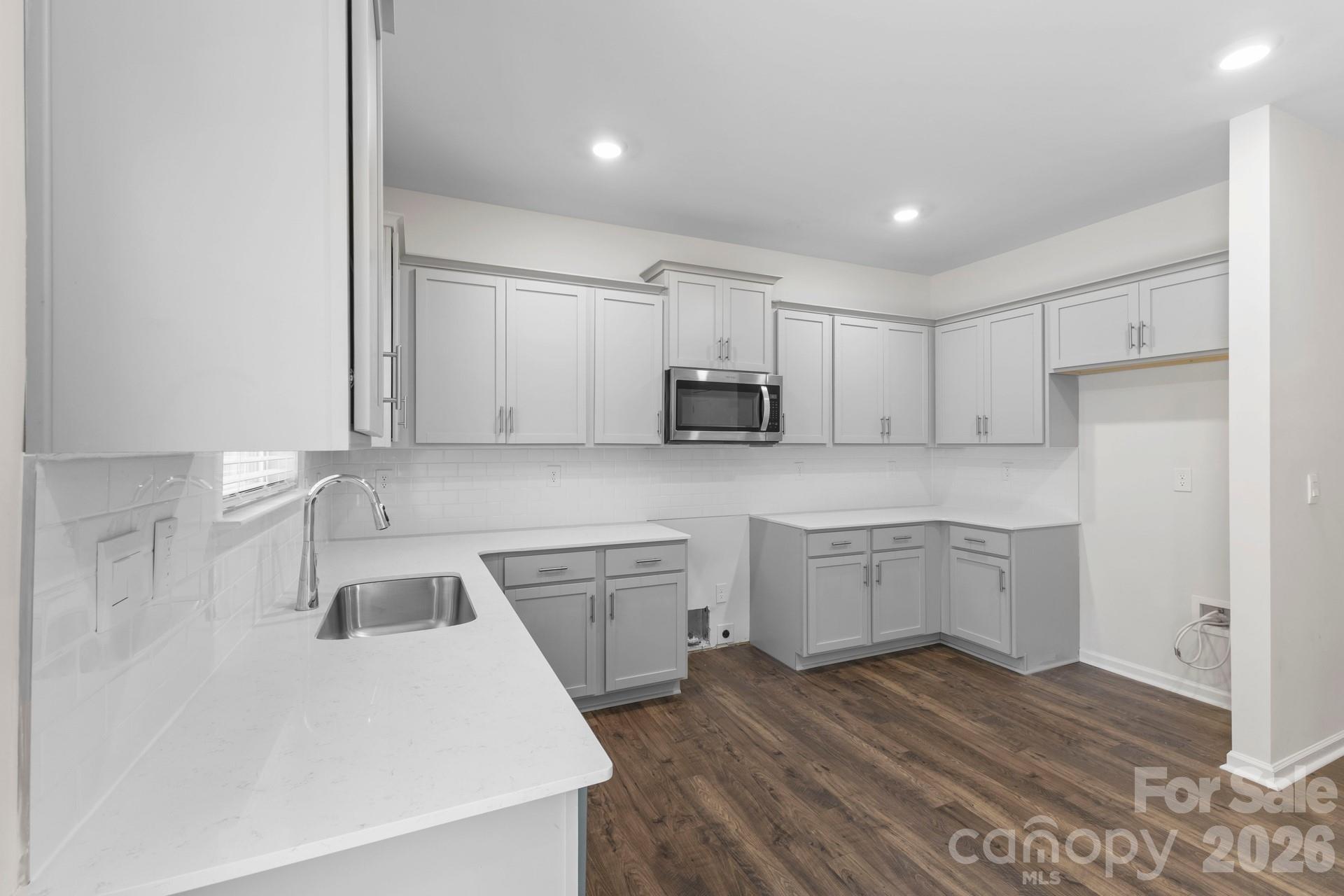 The kitchen is a true standout, showcasing upgraded gray soft-close cabinetry finished with elegant crown trim and equipped with a stainless steel dishwasher and over-the-range microwave. With a gas stove hookup and ice-maker connection already in place, this stylish space is ready for you to add your personal touch. - 3741 Stanley Creek Drive, Mount Holly