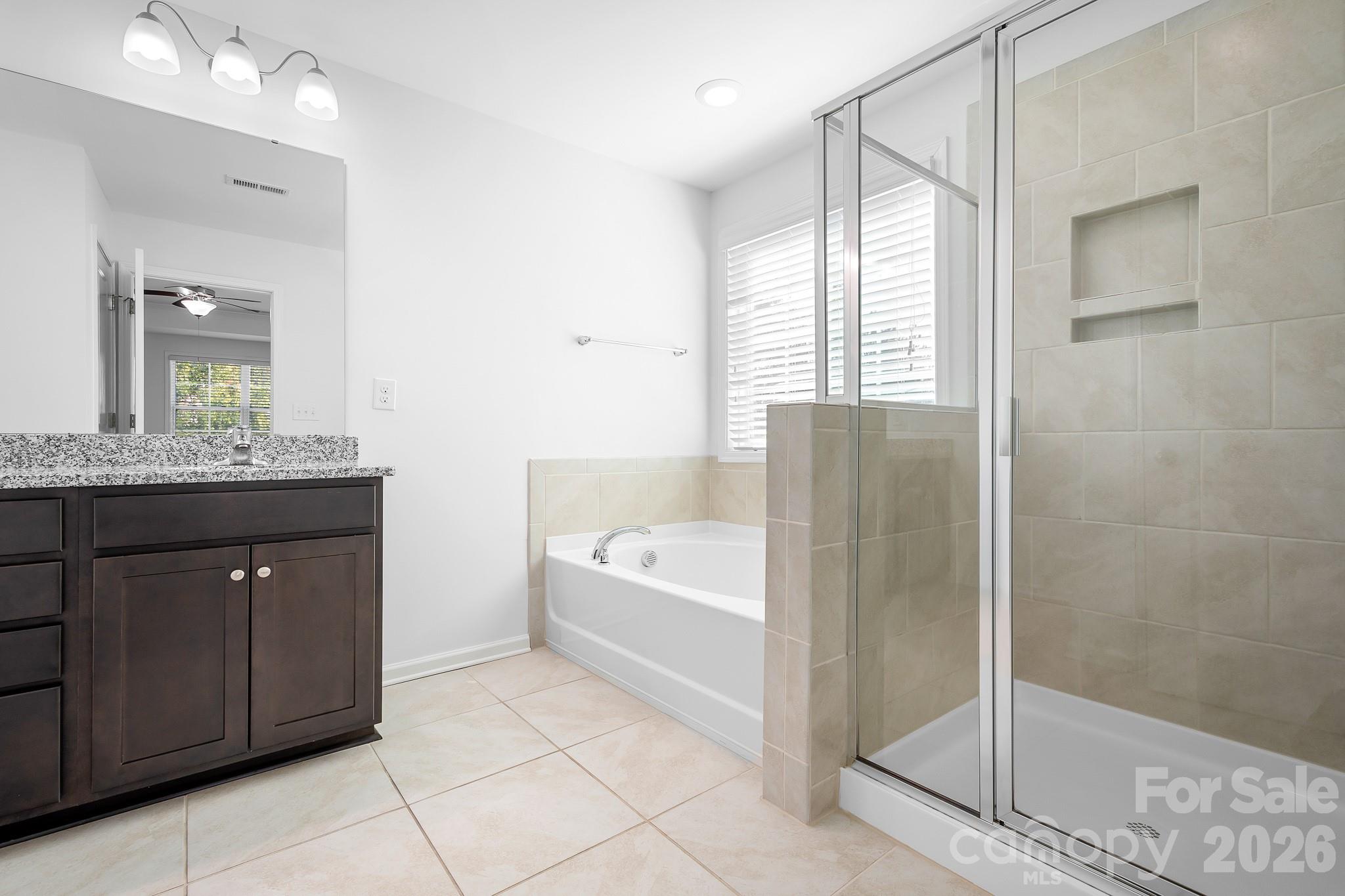 The spacious primary bath offers the best of both worlds, a large walk-in tiled shower and a separate soaking tub, perfect for relaxing at the end of the day. - 3967 Lake Breeze Drive, Sherrills Ford