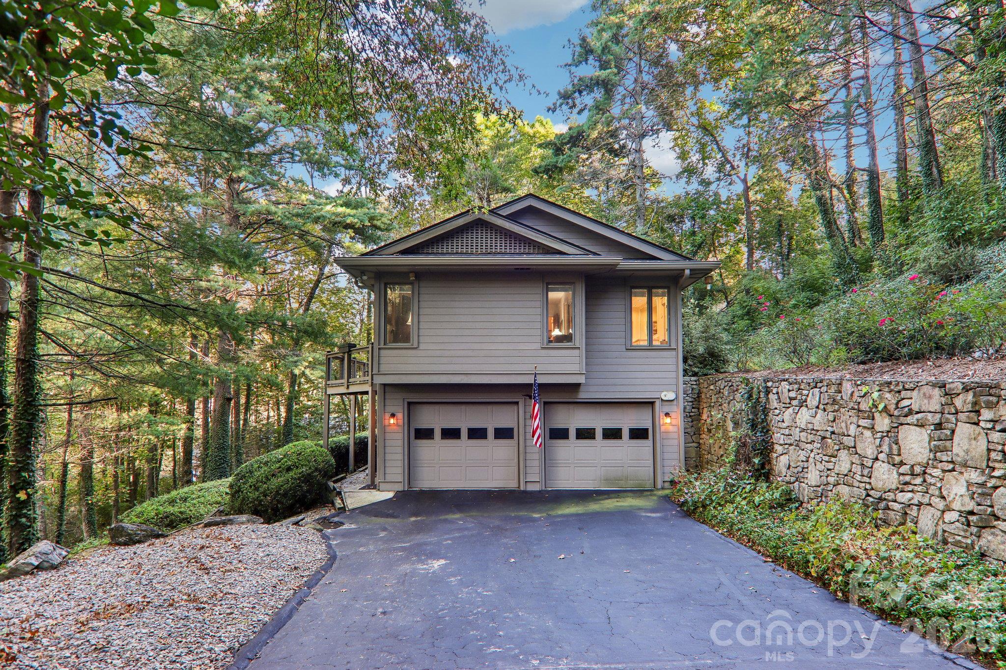 Side of the home with garage entry. Natural rock retaining wall accents the rock work on the home. - 212 Pheasant Run, Hendersonville