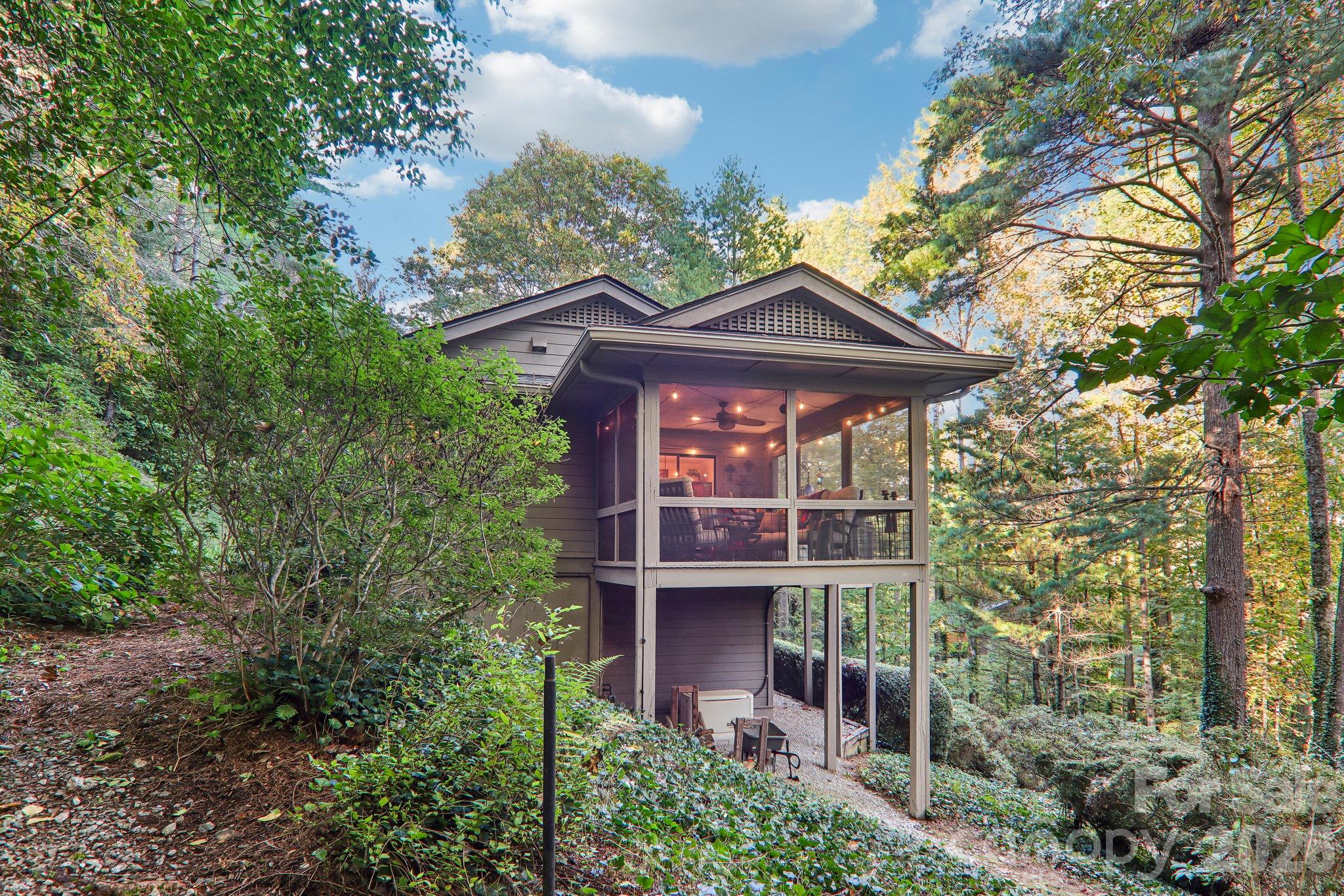 Side of home showcasing the screen porch and natural landscape - 212 Pheasant Run, Hendersonville