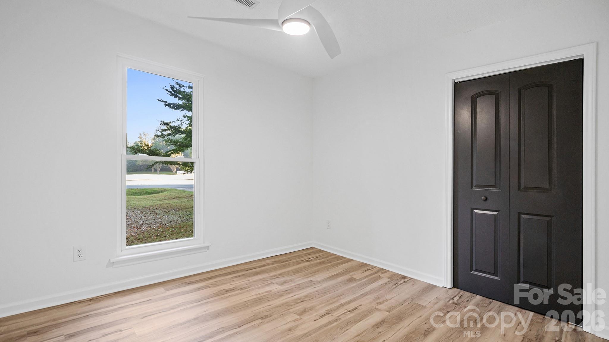 Second Bedroom Showcasing New Floors, New Ceiling Fan, and Sleek Urbane Bronze Painted Doors - 8001 Saddlehorse Lane, Charlotte
