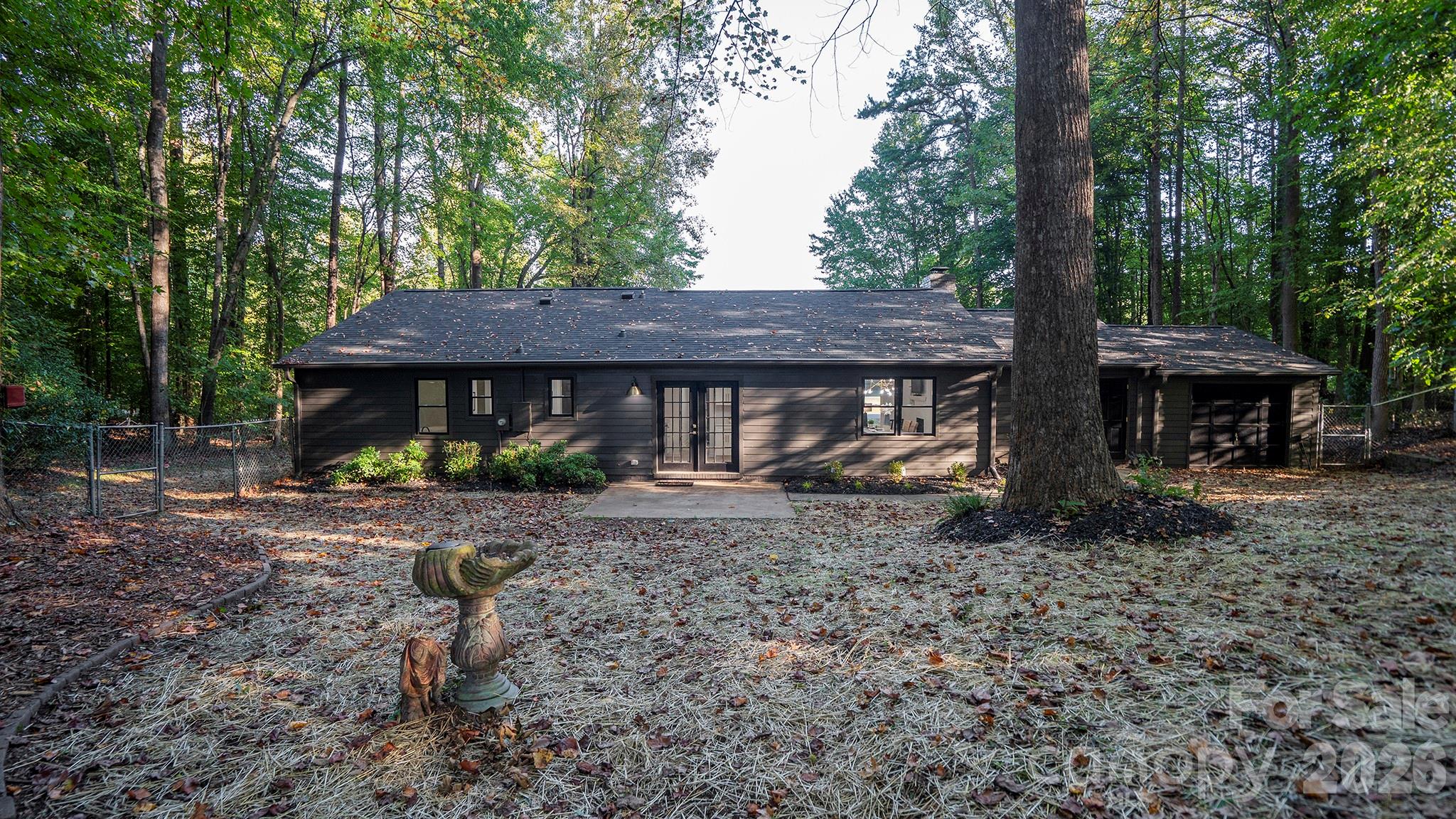 Back View of Home Featuring Relaxing Rear Patio Overlooking the Private Tree Lined Backyard - 8001 Saddlehorse Lane, Charlotte
