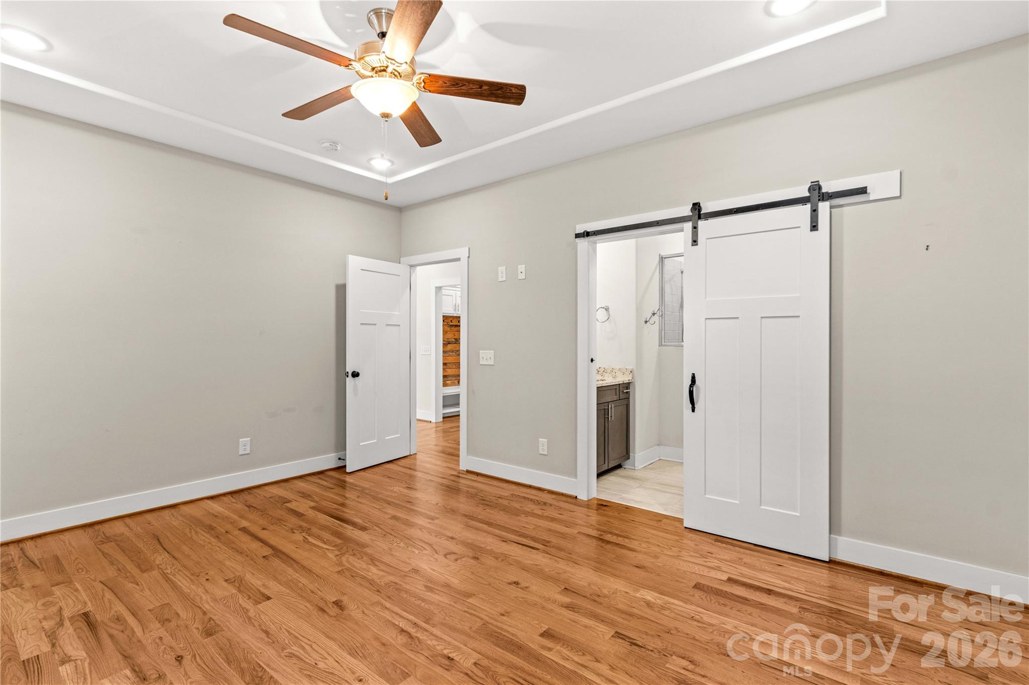 Primary bedroom with tray ceiling and sliding door leading to en suite bathroom. Dual entrance to large walk-in closet - 178 Nellwood Court, Mocksville