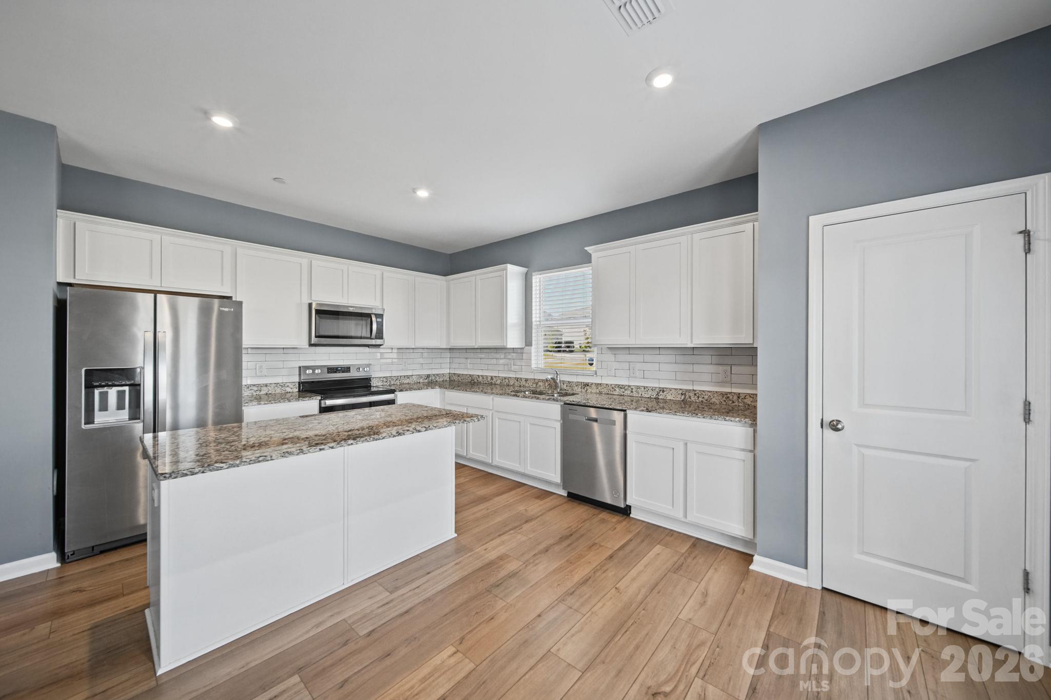 Kitchen, with it's gray walls, beautiful white cabinetry and Stainless Steel Appliances. All appliances convey - including Refrigerator, Microwave, Oven/Stove and Diswasher. - 3082 Bell Spur Avenue SW, Concord