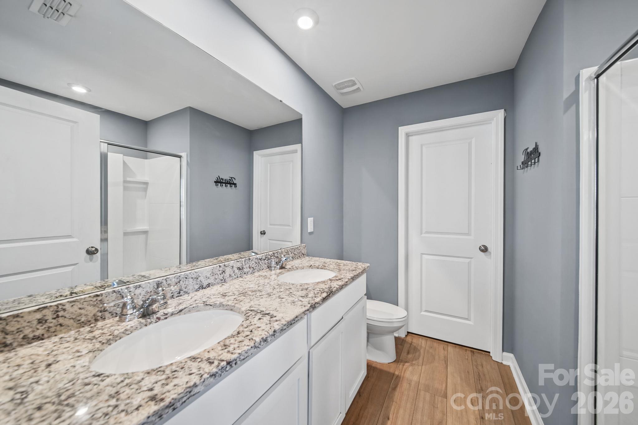 Large Primary Bath with 2 Sinks, Granite Countertops, White Cabinetry and Luxury Vinyl Plank Floors. - 3082 Bell Spur Avenue SW, Concord