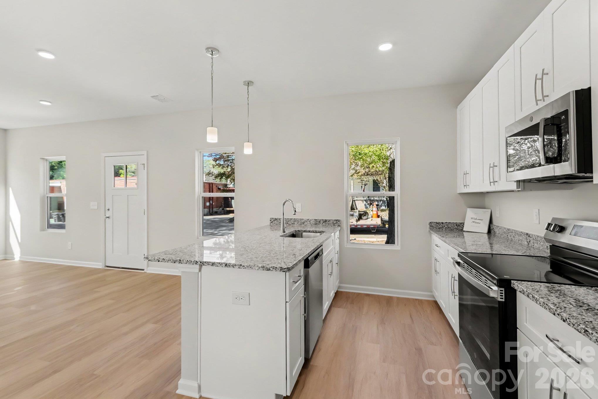 Kitchen features stainless steel farm style sink with granite island, disposal, dishwasher, electric range and microwave. Pendant lighting and recessed lighting offers a modern feel and soft close drawers and cabinet doors add to the list of features. - 125 Buffalo Avenue NW, Concord