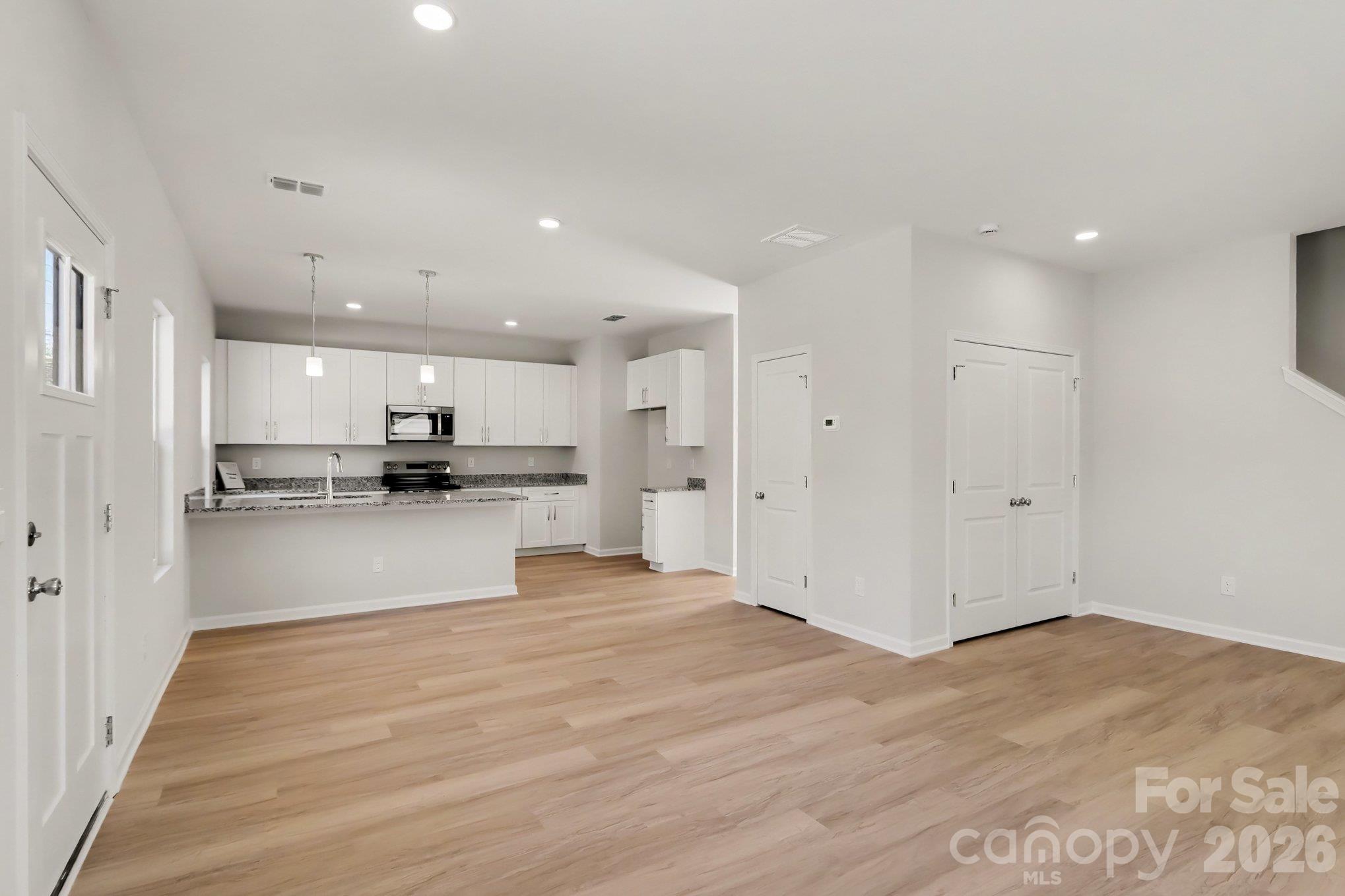 Great room & dining area. Kitchen has pantry. Great room has a storage closet. Half bath is also located on main level across from the office in the hallway leading to the back deck. Actual photo. - 125 Buffalo Avenue NW, Concord