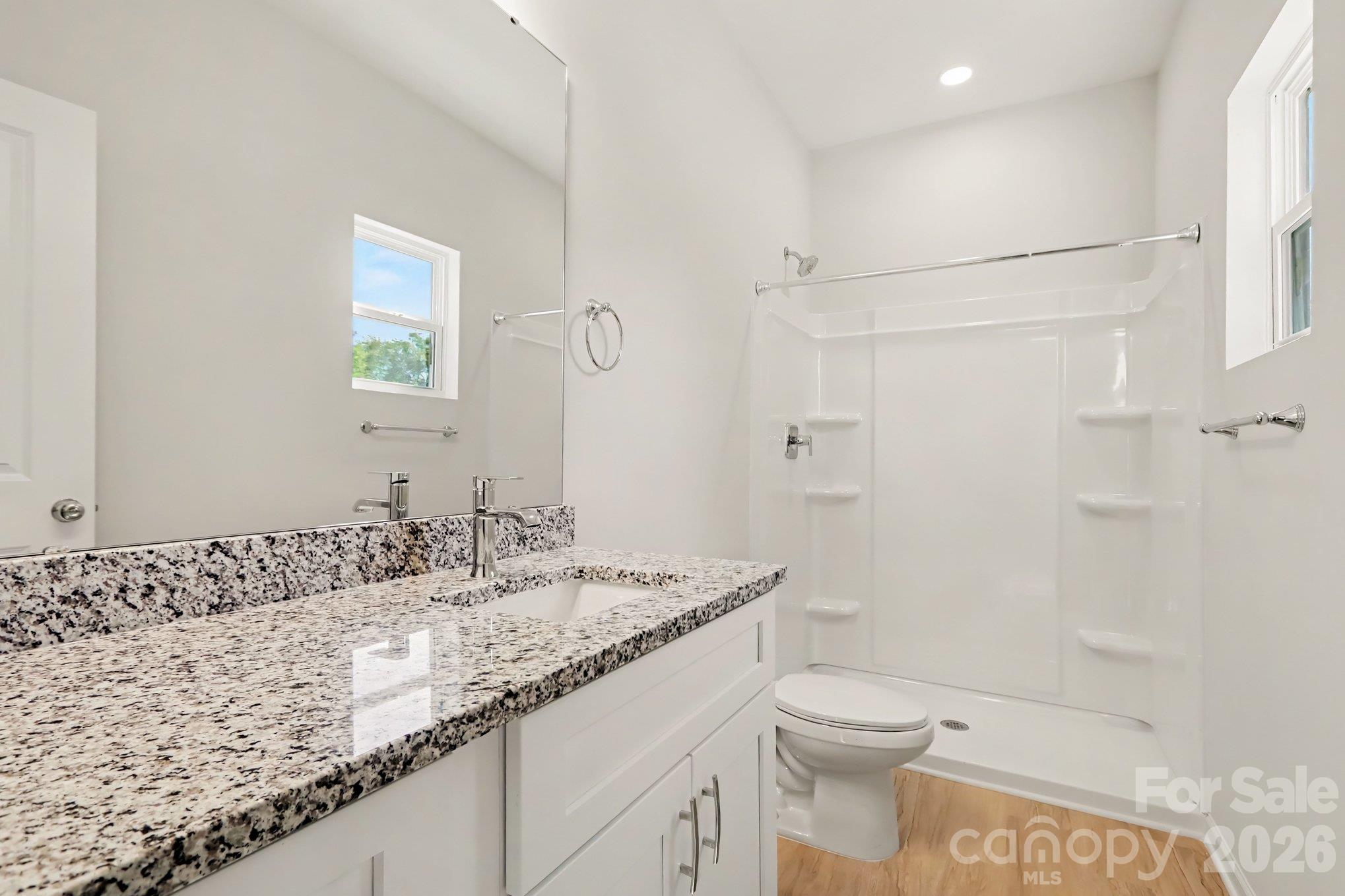 Primary ensuite bathroom with single vanity with granite countertop and a walk in shower. Actual non-staged photo. - 125 Buffalo Avenue NW, Concord