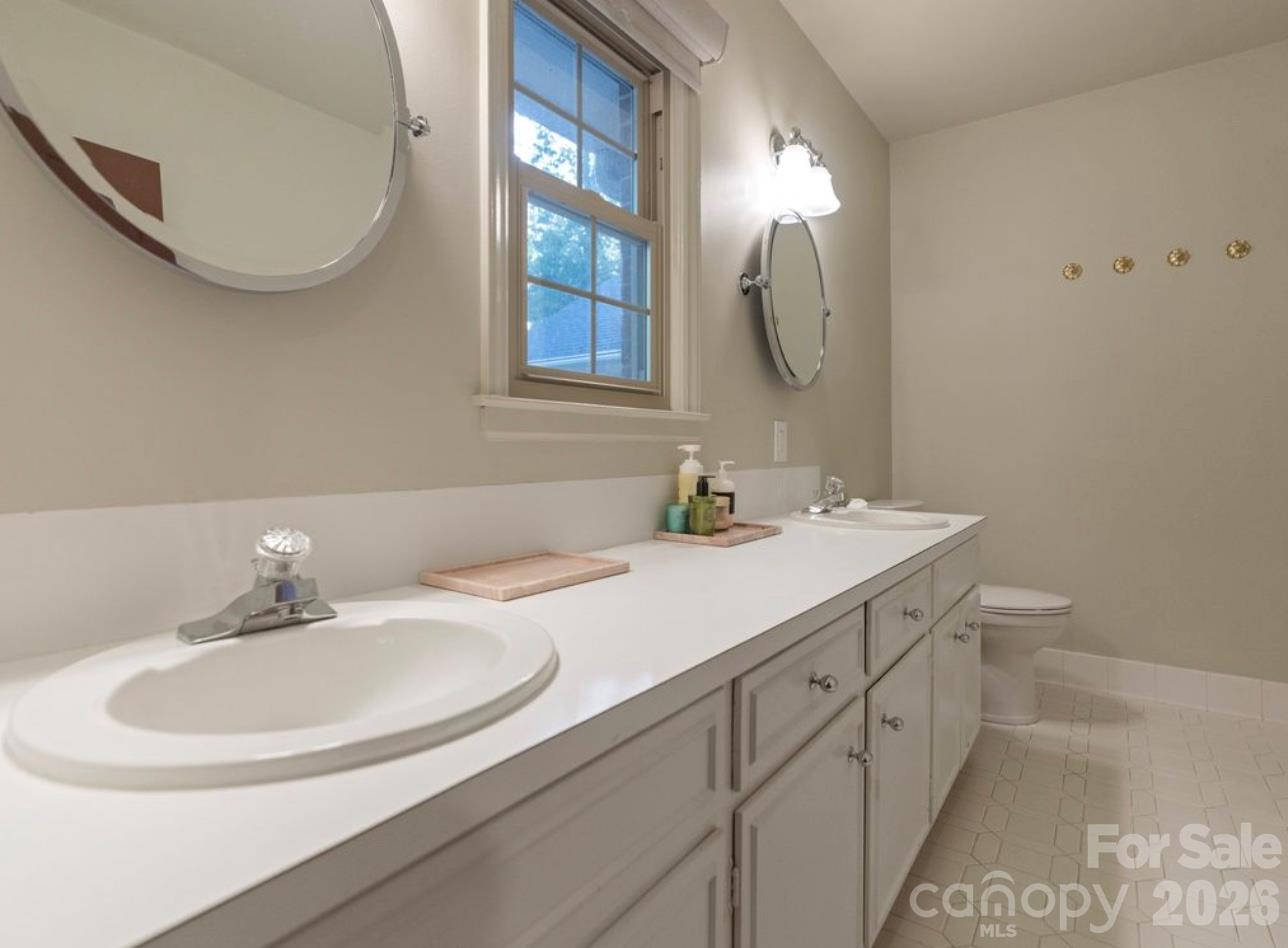 The ensuite bathroom features updated mirrors and modern lighting, adding a fresh, contemporary touch to the primary suite. - 6626 Rocky Falls Road, Charlotte