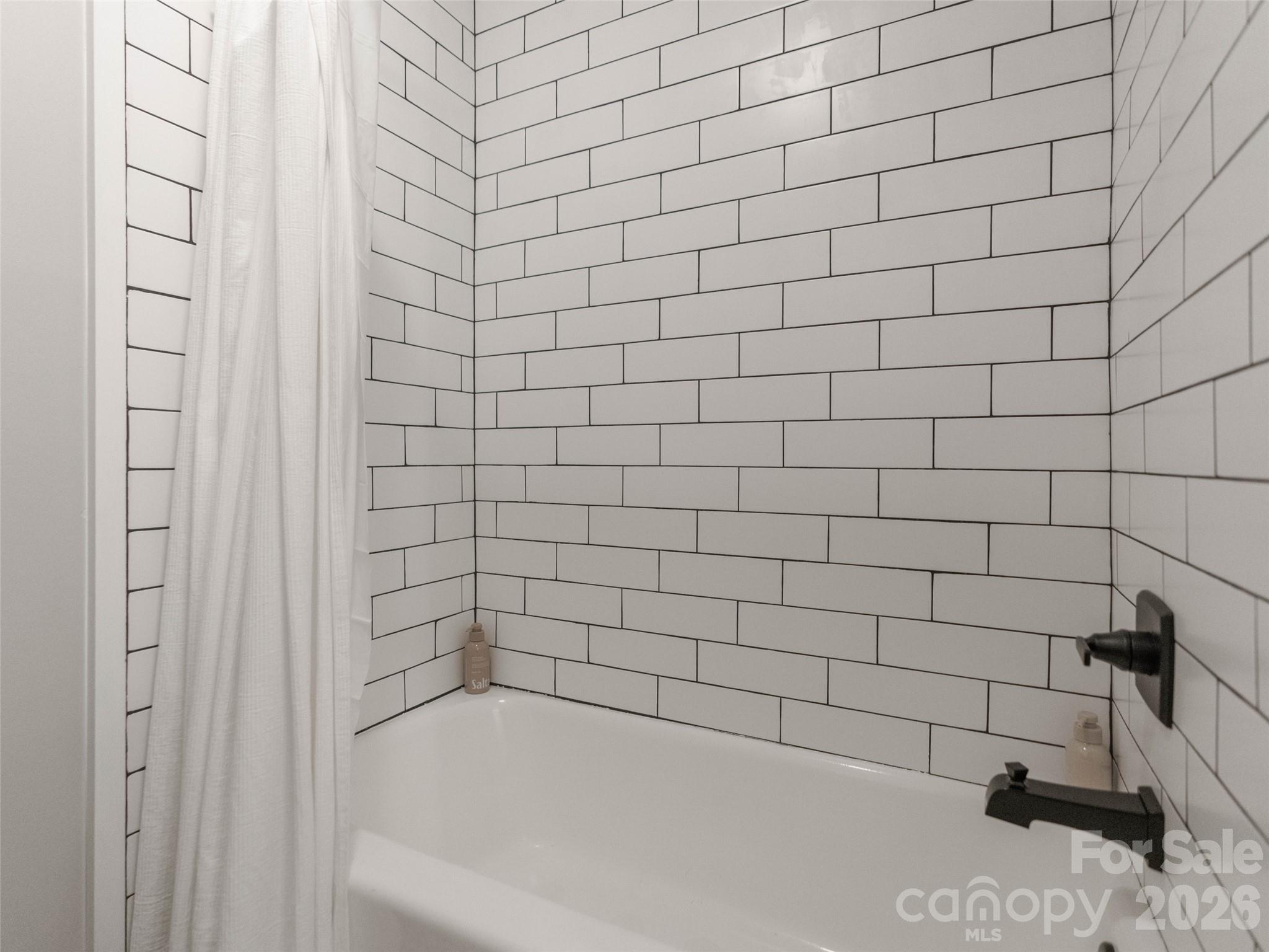 Beautiful, stylish tile and updated faucets bring a touch of contemporary elegance to this refreshed hallway bathroom. - 6626 Rocky Falls Road, Charlotte