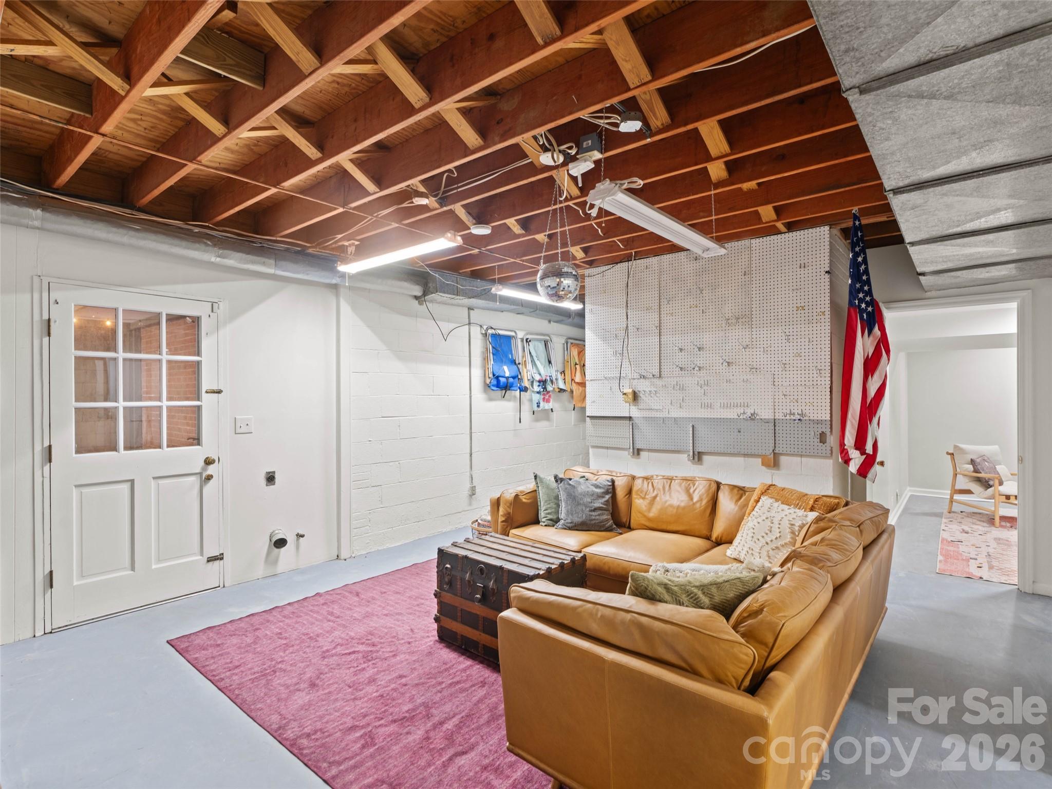 The possibilities are endless in this heated and cooled basement flex space! While this space is NOT included in the home’s official heated living area (HLA), it is currently showcased as a fun hangout area. This versatile space could easily be transformed into a media room, playroom, hobby area, or additional storage. The door shown provides convenient access to the covered patio, extending your options for relaxation and entertaining. - 6626 Rocky Falls Road, Charlotte