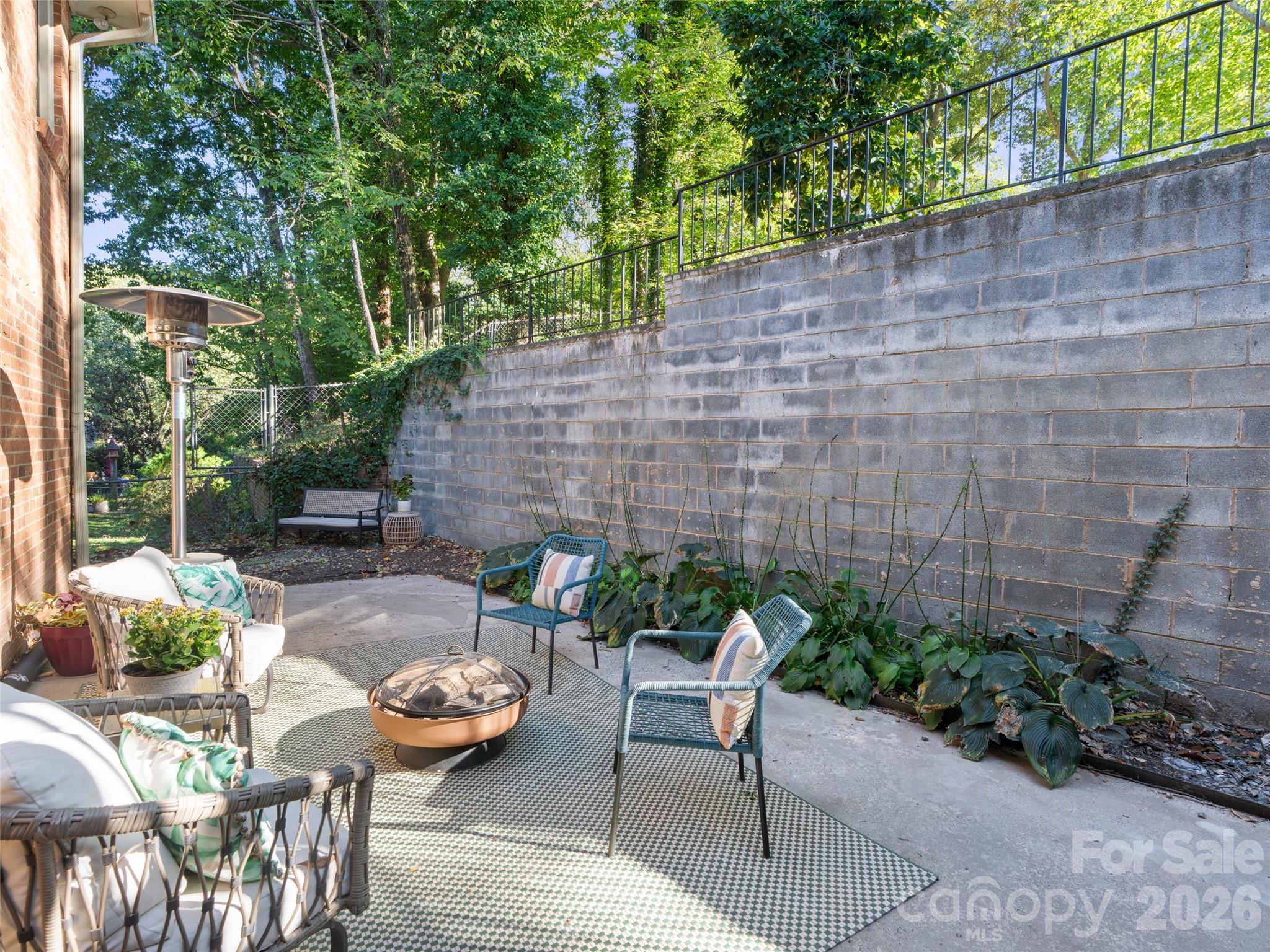 Enjoy a cozy lower-level patio, perfect for relaxing outdoors or creating an inviting seating area. Just beyond the bench, a connecting sidewalk leads directly to the lower-level parking pad, providing convenient access and additional parking for guests or household members. - 6626 Rocky Falls Road, Charlotte
