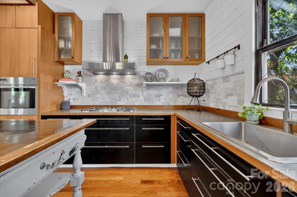 Warm mahogany cabinetry, a wall oven, and a gas cooktop keep everything within reach, so cooking feels easy. The island is steps away, so the cook is part of the conversation.The Miele range and oven offer a sleek look to this modern space. - 521 Forest Lane, Rock Hill