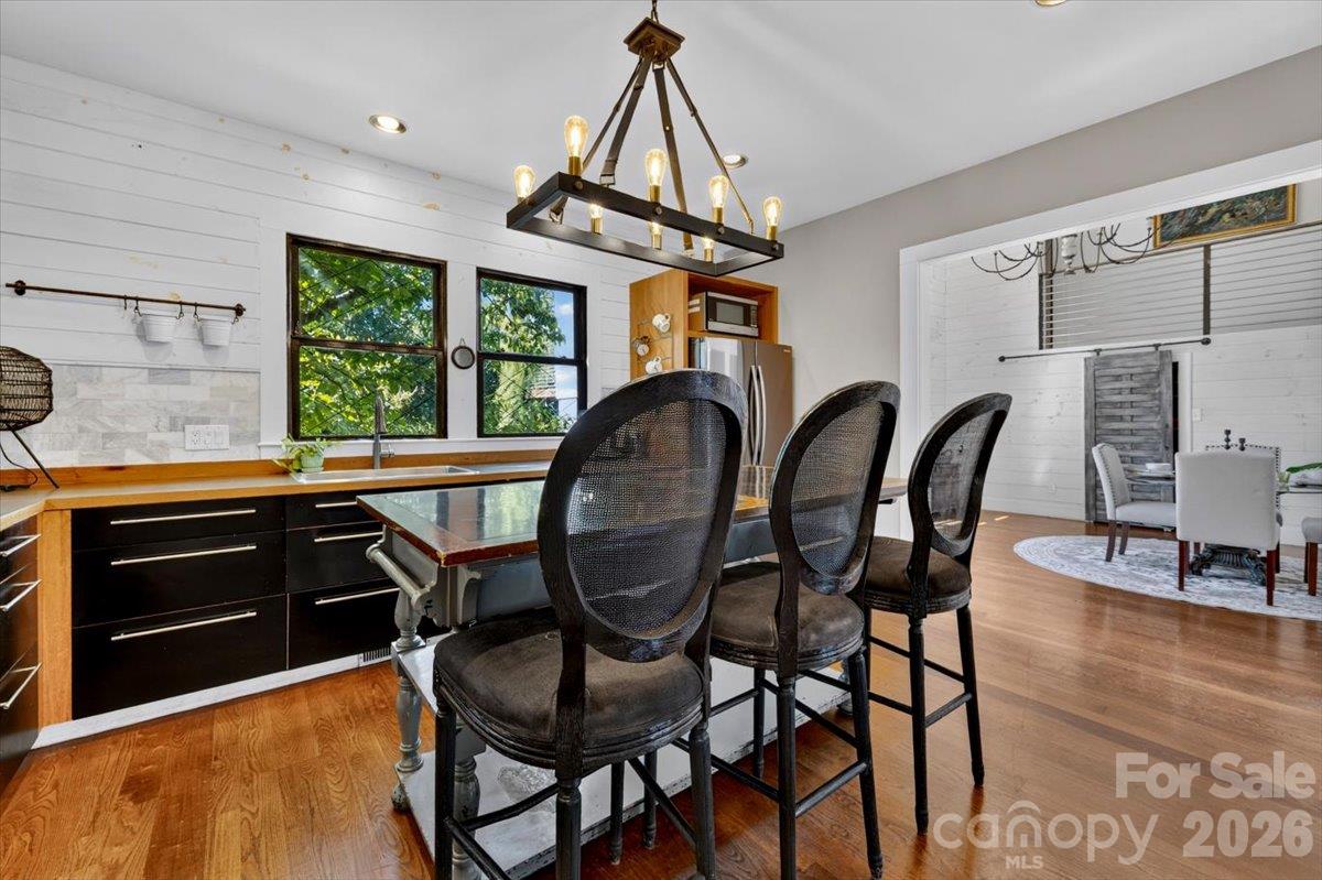 Open sightlines run from the island to the dining room, so a dinner party flows between rooms. Hardwood floors, shiplap, and leafy views make every meal feel relaxed. - 521 Forest Lane, Rock Hill