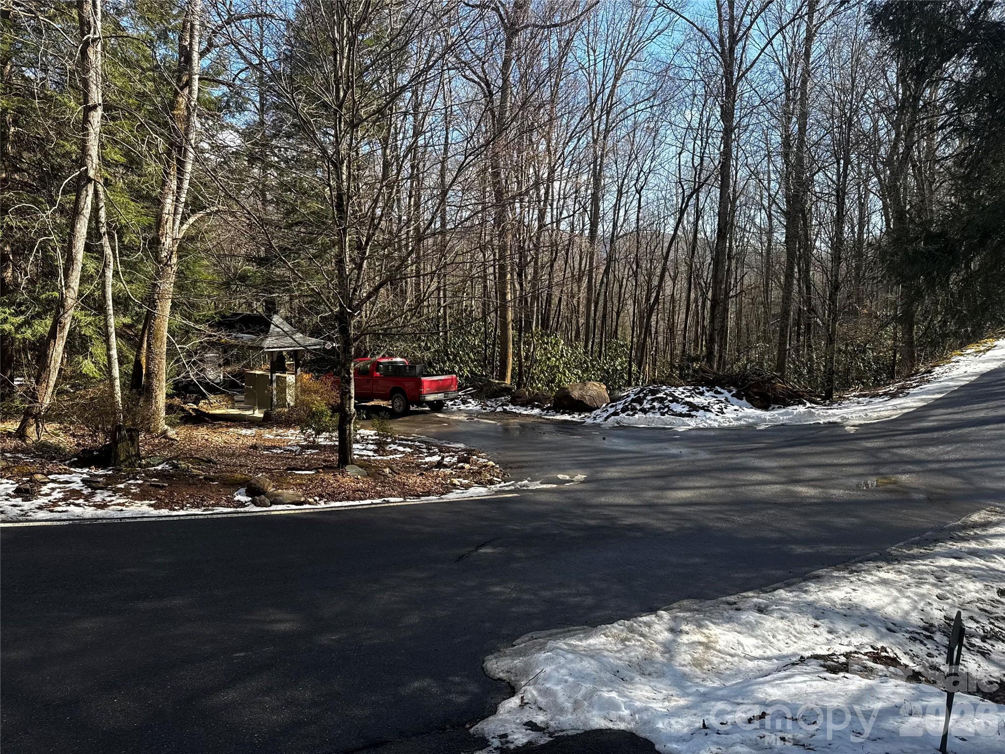 The stream that goes by the house-site, in front of the virtual home, goes under the land bridge shown here, culvert and drainage is located behind and to the right of the parked red truck, below the grade of the road... - 6 Great Aspen Way, Black Mountain