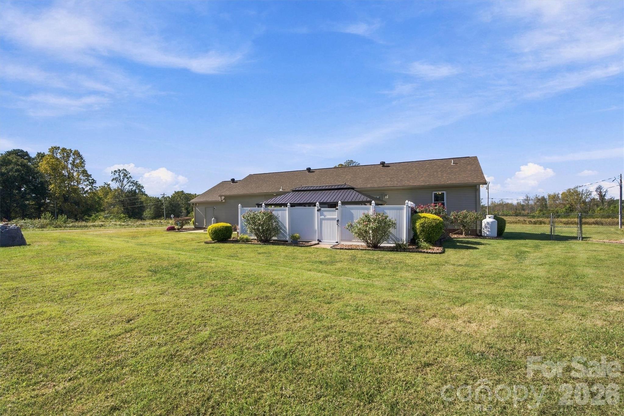 Another view of rear of home showcases the beautiful level lot that is cleared of trees. Chain link fence with gate connects to fencing on the left and rear property lines. - 643 Shoal Road, Lincolnton