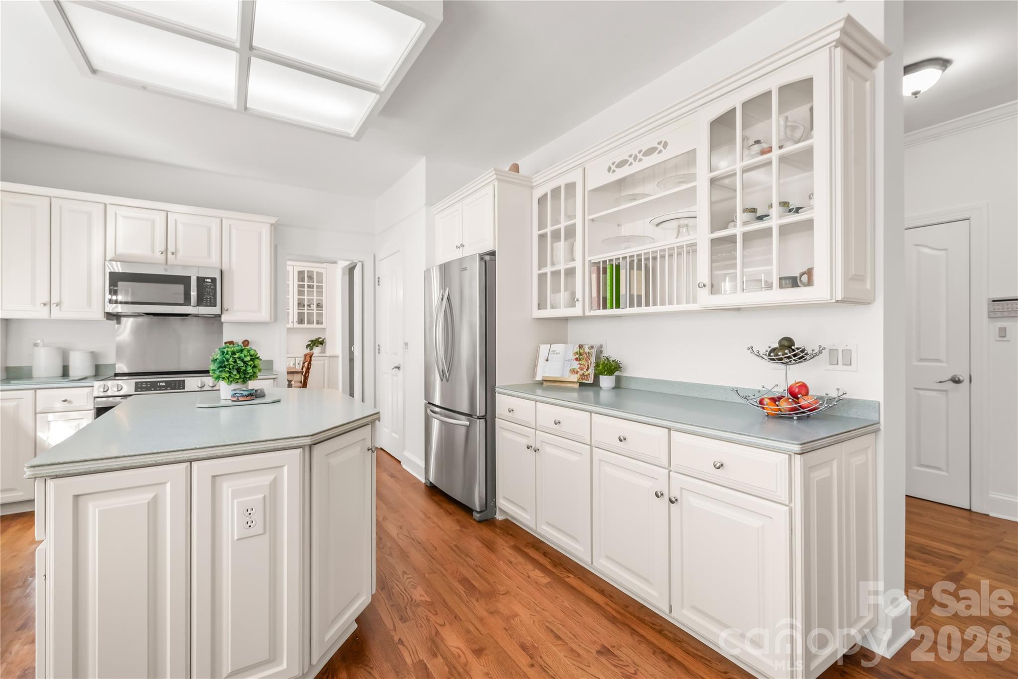 Upper glass-front cabinetry brings depth, light, and timeless sophistication to the kitchen. - 11024 Stonepath Lane, Charlotte
