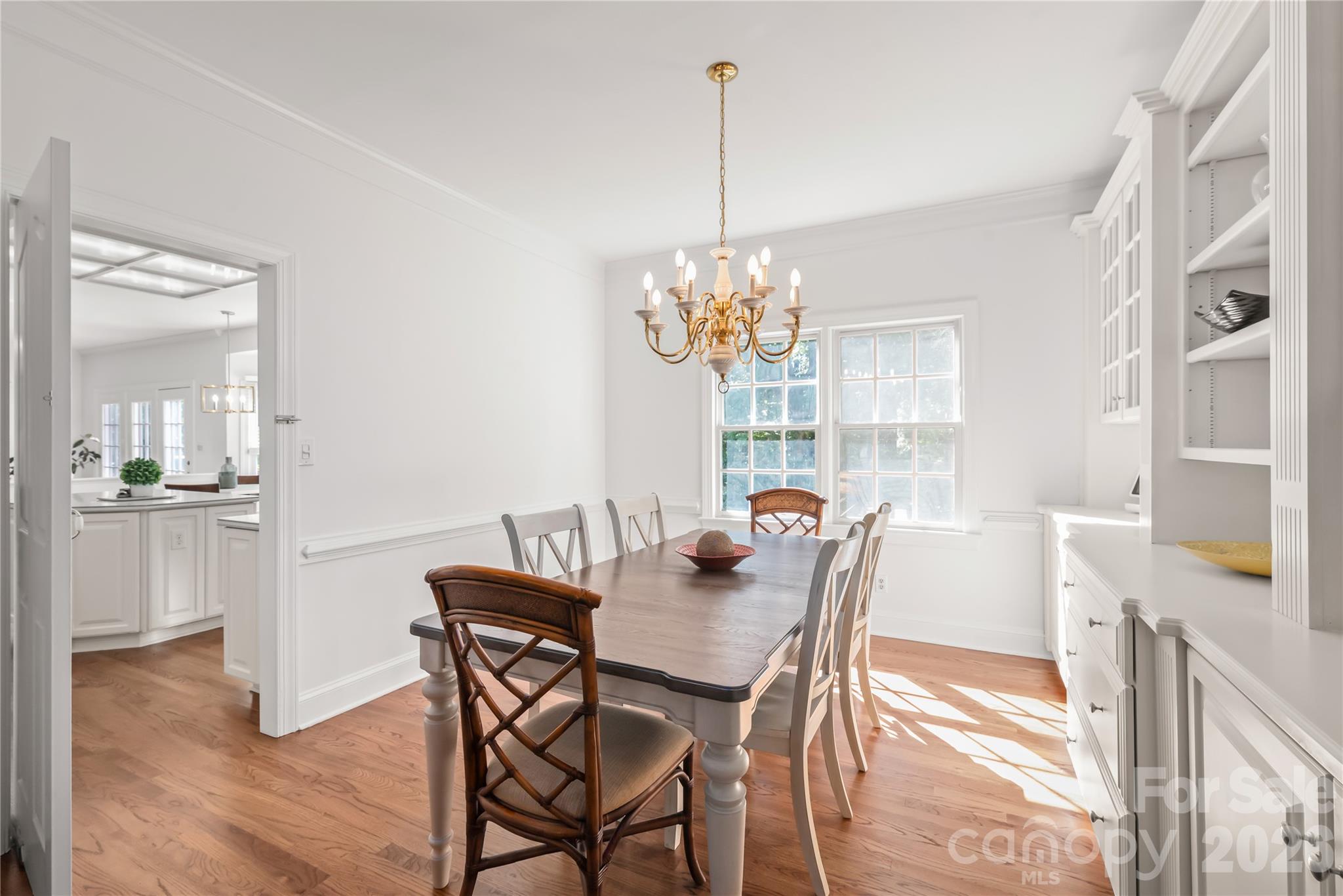 This stunning formal dining room features custom built-ins for effortless storage and display, grounded by rich, newly finished hardwood floors. - 11024 Stonepath Lane, Charlotte