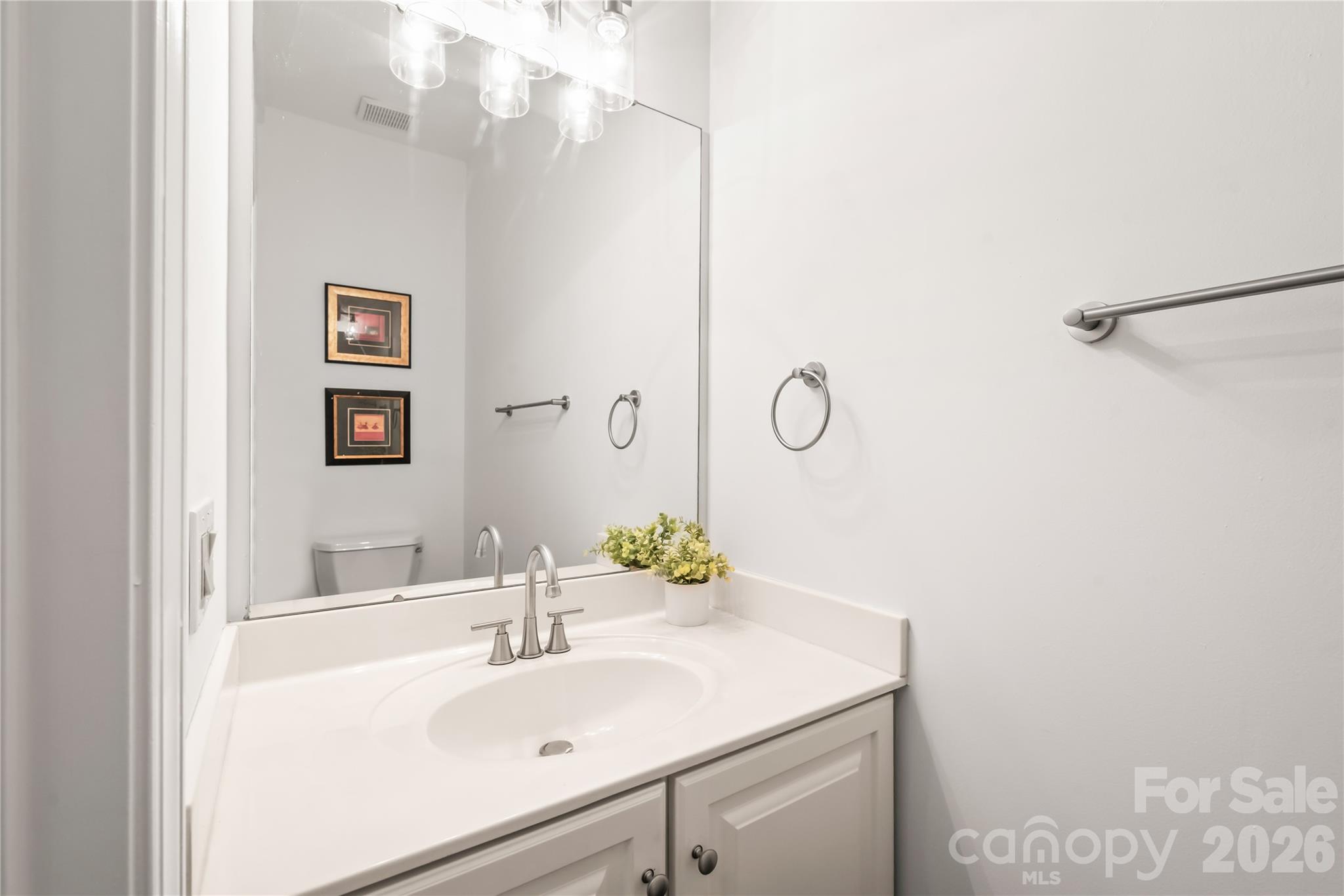 The main-level powder room features an updated faucet and stylish lighting fixtures for a refreshed look. - 11024 Stonepath Lane, Charlotte
