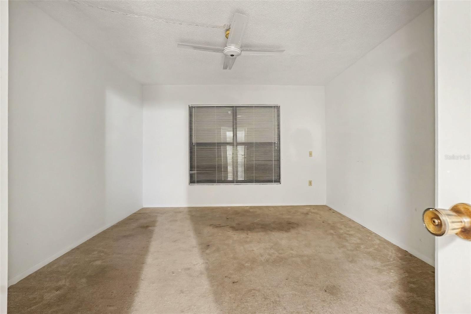 Guest bedroom with ceiling fan, carpet, and window with blinds for natural light. - 1423 MEDITERRANEAN DR #B, PUNTA GORDA