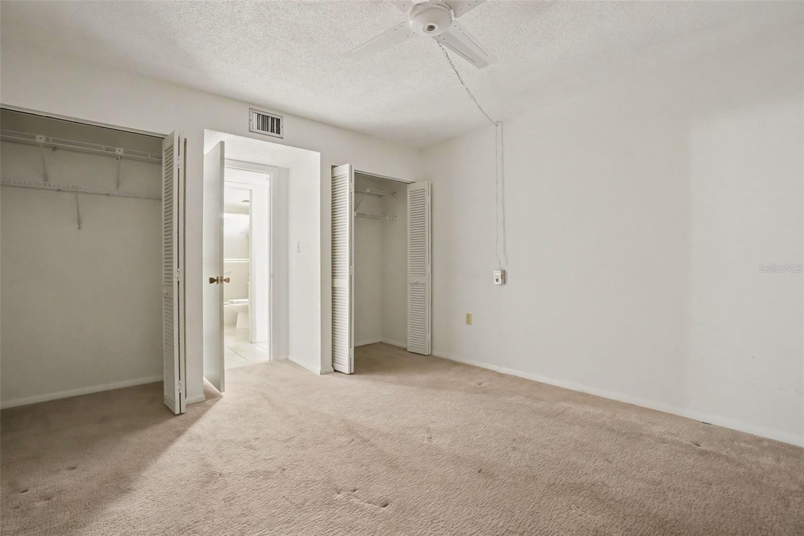 Guest bedroom with two closets with bifold doors, ceiling fan, and easy access to the guest bathroom. - 1423 MEDITERRANEAN DR #B, PUNTA GORDA