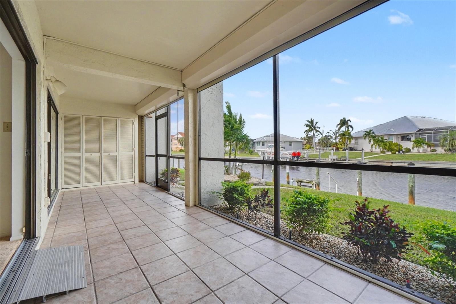 Large screened lanai with tile flooring and electric roll-down shutters, facing the canal and private dock. - 1423 MEDITERRANEAN DR #B, PUNTA GORDA