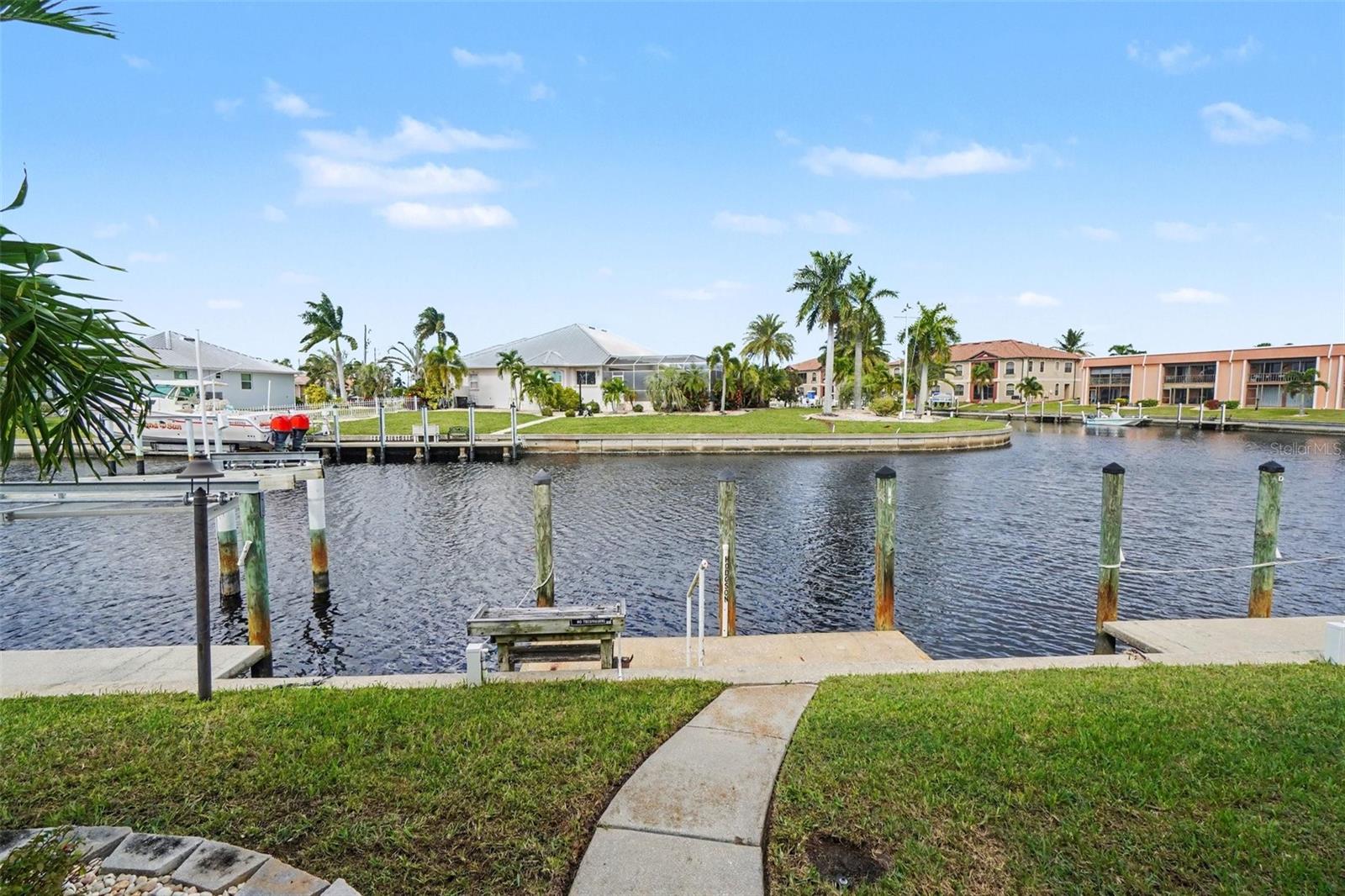 Canal view from the backyard of this Punta Gorda waterfront condo, with the private dock, seawall, and neighboring boat lifts across the water. - 1423 MEDITERRANEAN DR #B, PUNTA GORDA