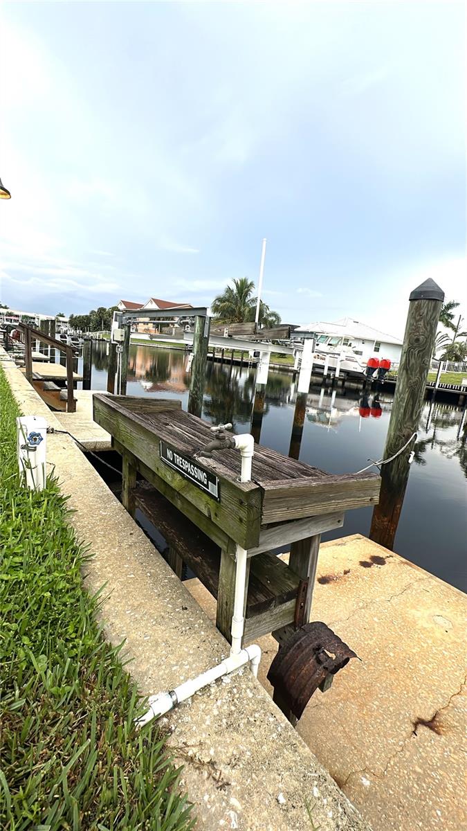 Close-up of the deeded dock with storage box, cleats, and pilings along the seawall. - 1423 MEDITERRANEAN DR #B, PUNTA GORDA