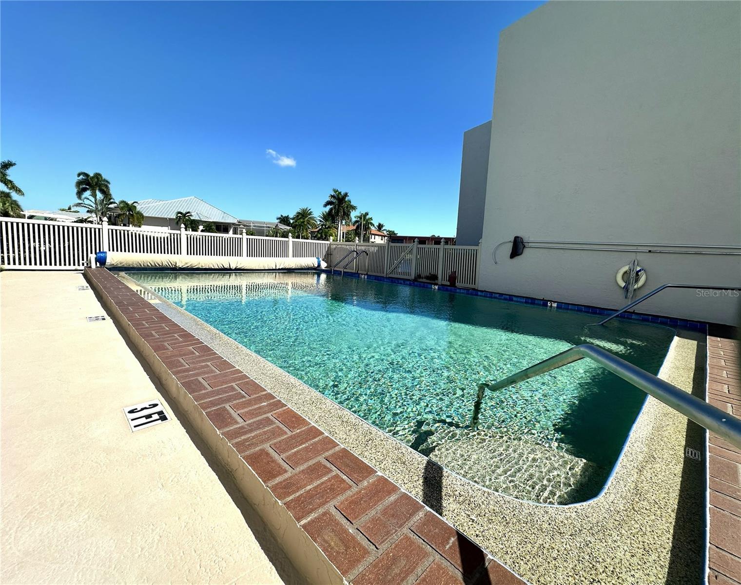Heated community pool with brick paver coping, handrail entry steps, and sun deck just off the canal. - 1423 MEDITERRANEAN DR #B, PUNTA GORDA