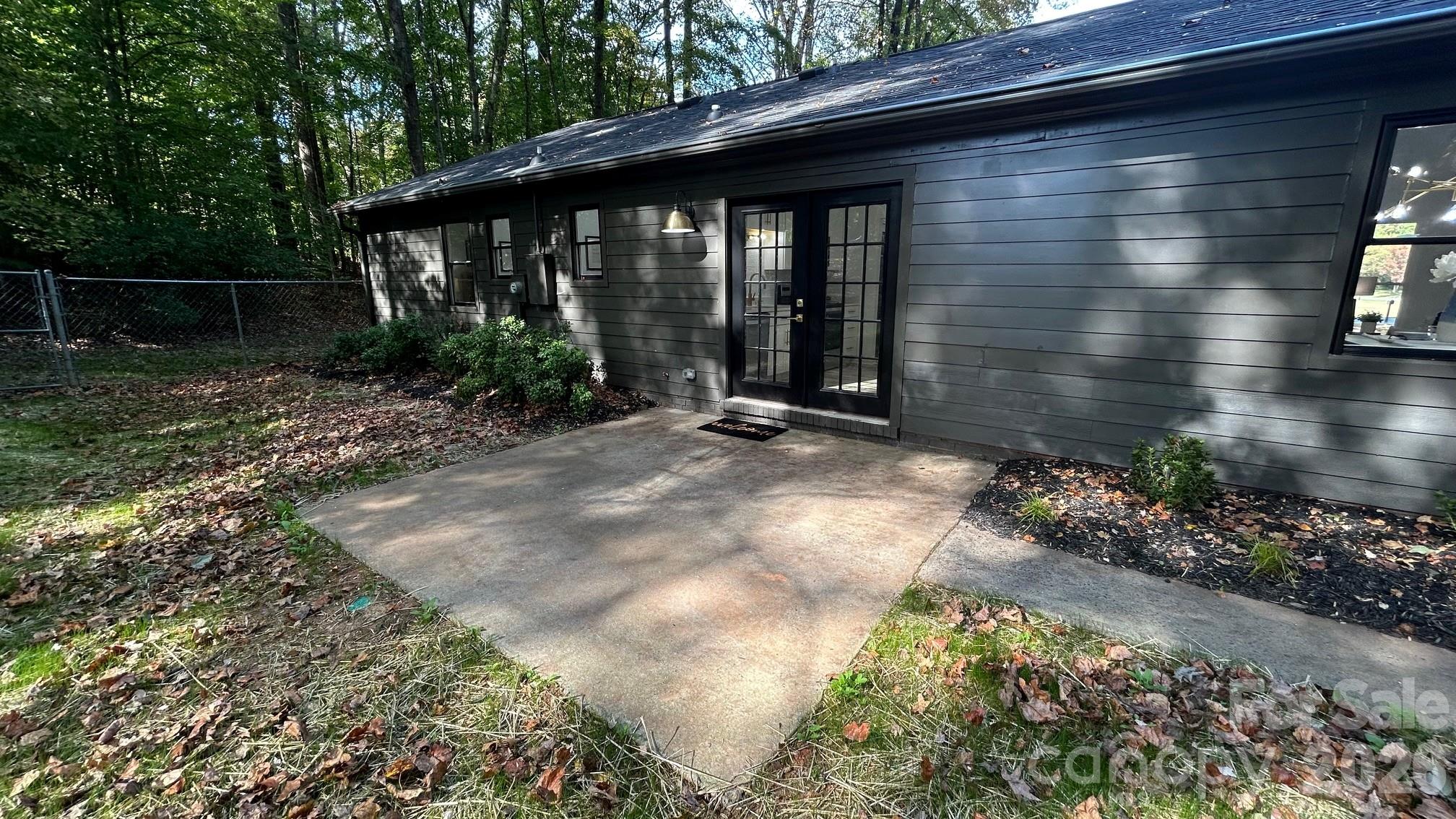 Back View of Home Featuring Relaxing Rear Patio Overlooking the Private Tree Lined Backyard - 8001 Saddlehorse Lane, Charlotte