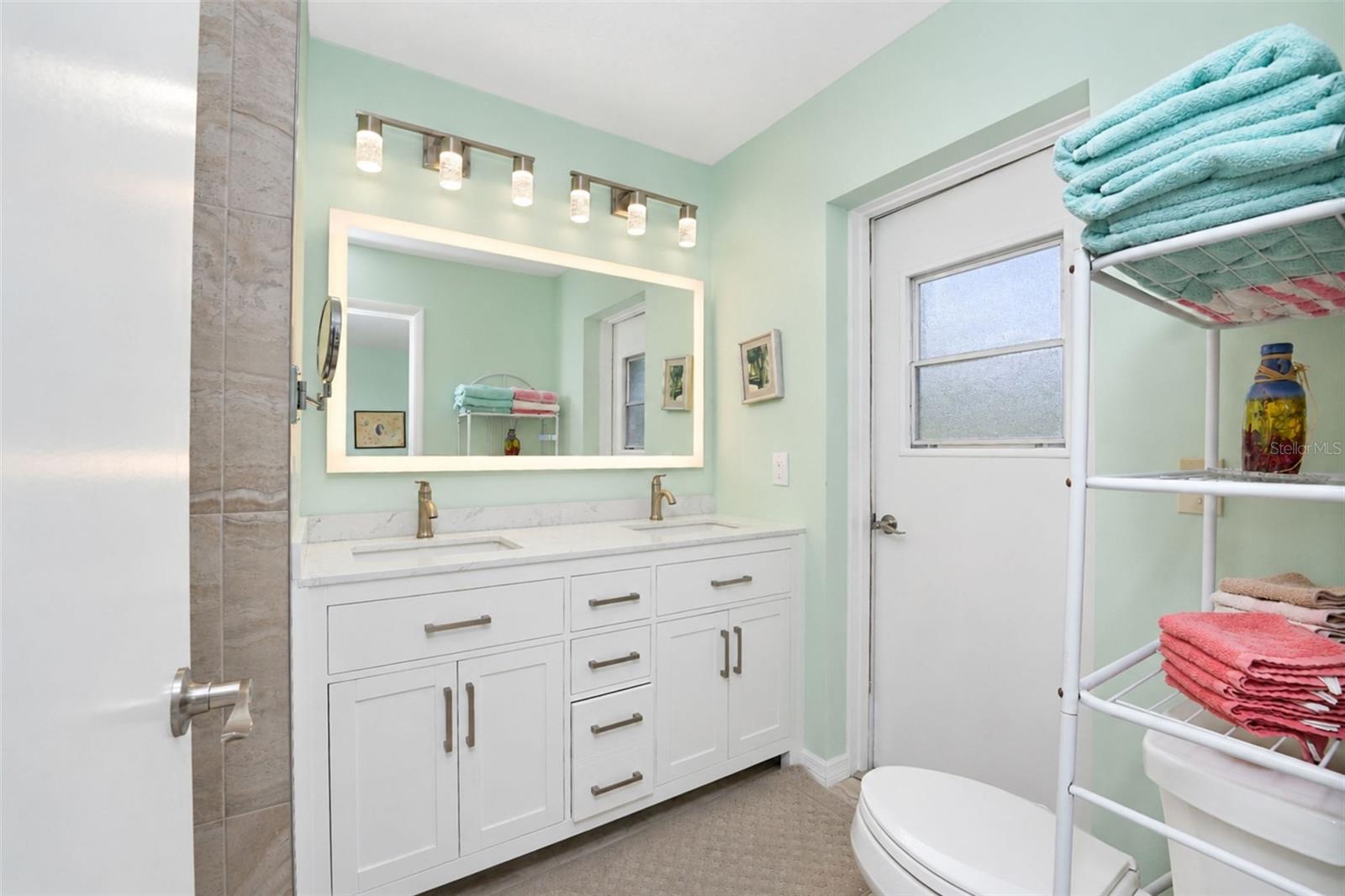 The updated ensuite bathroom features a new double sink vanity with solid-surface countertop, new faucets, touch control mirror, tiled flooring and direct access to the garage! - 6468 HAMLET DR #B, ENGLEWOOD