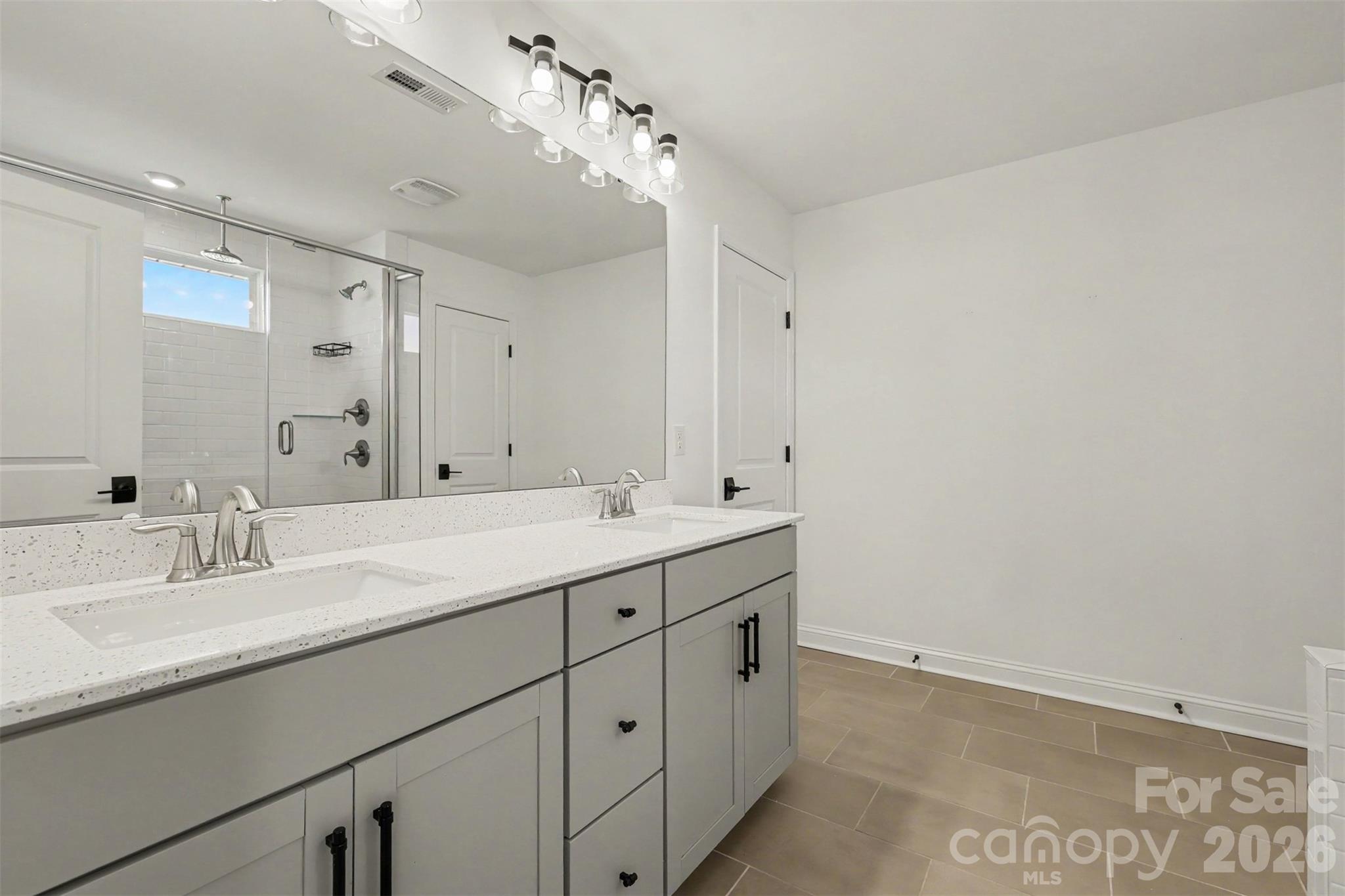 Upstairs Primary Bathroom with Tile Flooring, Walk In Shower, & Double Sink Vanity. - 11016 Larkslea Lane, Charlotte
