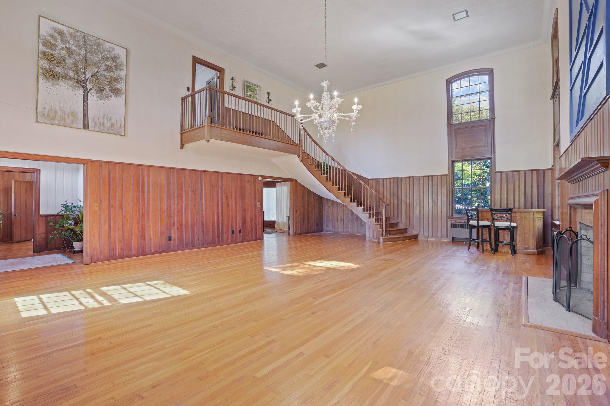 Grand Living Room, 3/4" Thick, Wood Panels Surround, Acoustic walls above, Staircase Ascends from Upstairs, Fireplace, Floor to Ceiling Storm Windows, Hardwood Floor, Adjacent to the Entry Foyer - 319 N Zion Street, Landis
