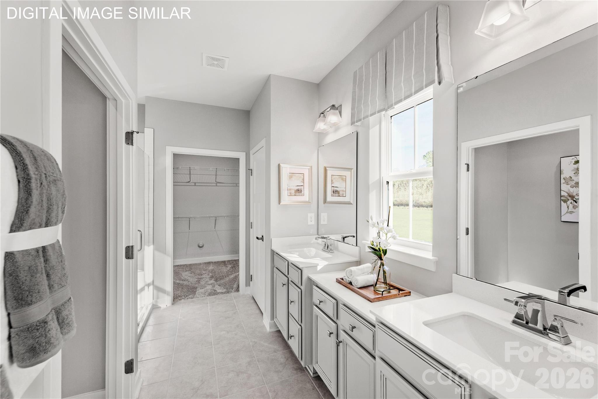 Bright primary bath with dual vanities, walk-in shower, and a spacious walk-in closet for everyday ease. - 11174 Emerson Landing Drive, Charlotte