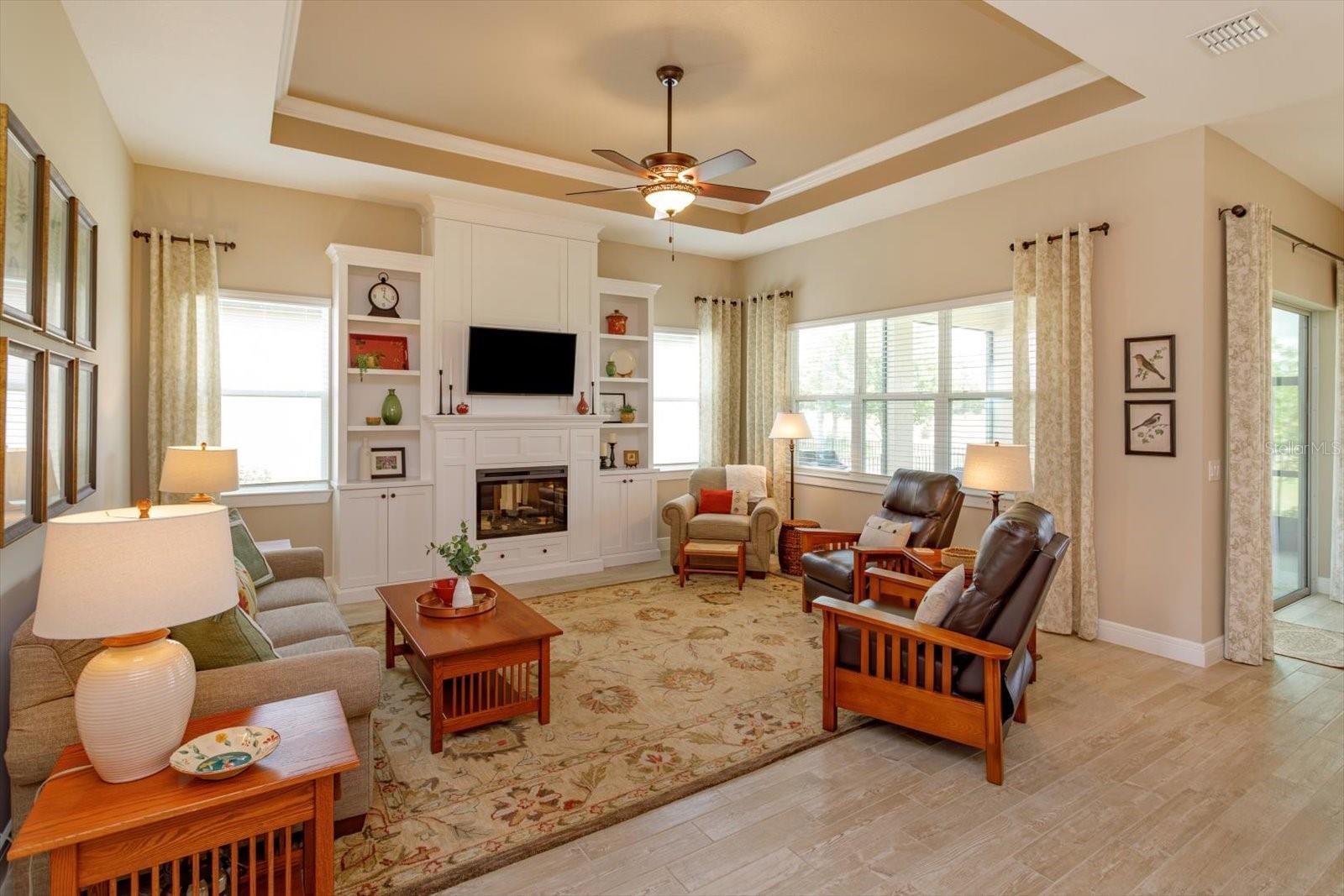 Living Room with Custom Built-in Cabinetry and Electric Fireplace. Designed with hidden storage on both sides of the fireplace and above the TV - 5663 SW 92ND AVENUE RD, OCALA