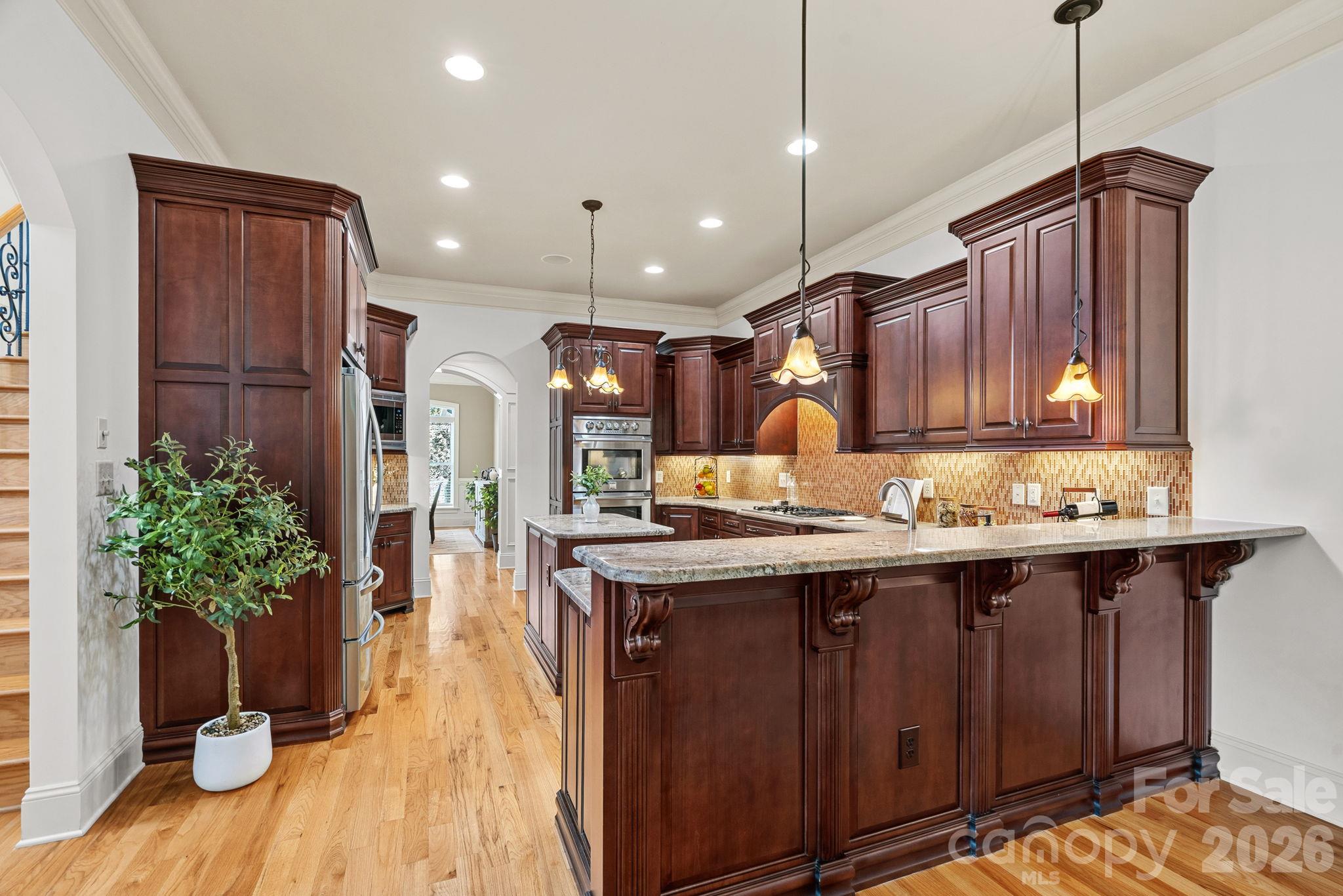 The kitchen is designed for both the daily chef and evening gatherers. Centered around an island, it is beautifully outfitted with custom cabinetry, under-cabinet lighting, and high-end stainless steel appliances, including a gas cooktop and double oven. - 108 Lazenby Drive, Fort Mill