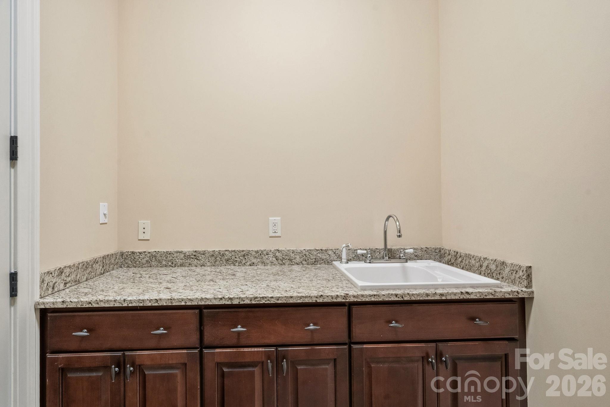 Main-level laundry room with granite folding table and sink - 108 Lazenby Drive, Fort Mill