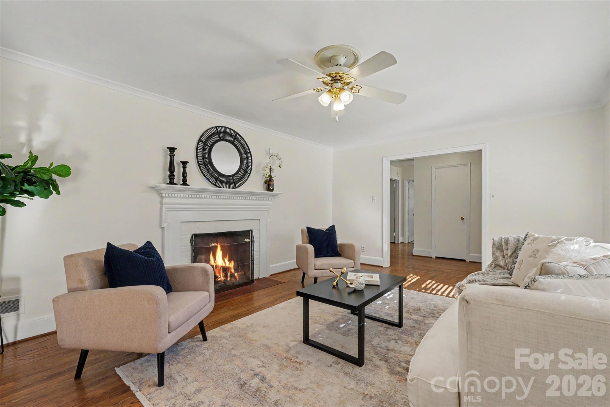 Another view of the inviting living room, featuring beautiful hardwood floors and a wood-burning fireplace. A perfect spot to gather and relax.Photo disclaimer: Fire digitally enhanced for illustrative purposes. - 407 Pine Street, Fort Mill
